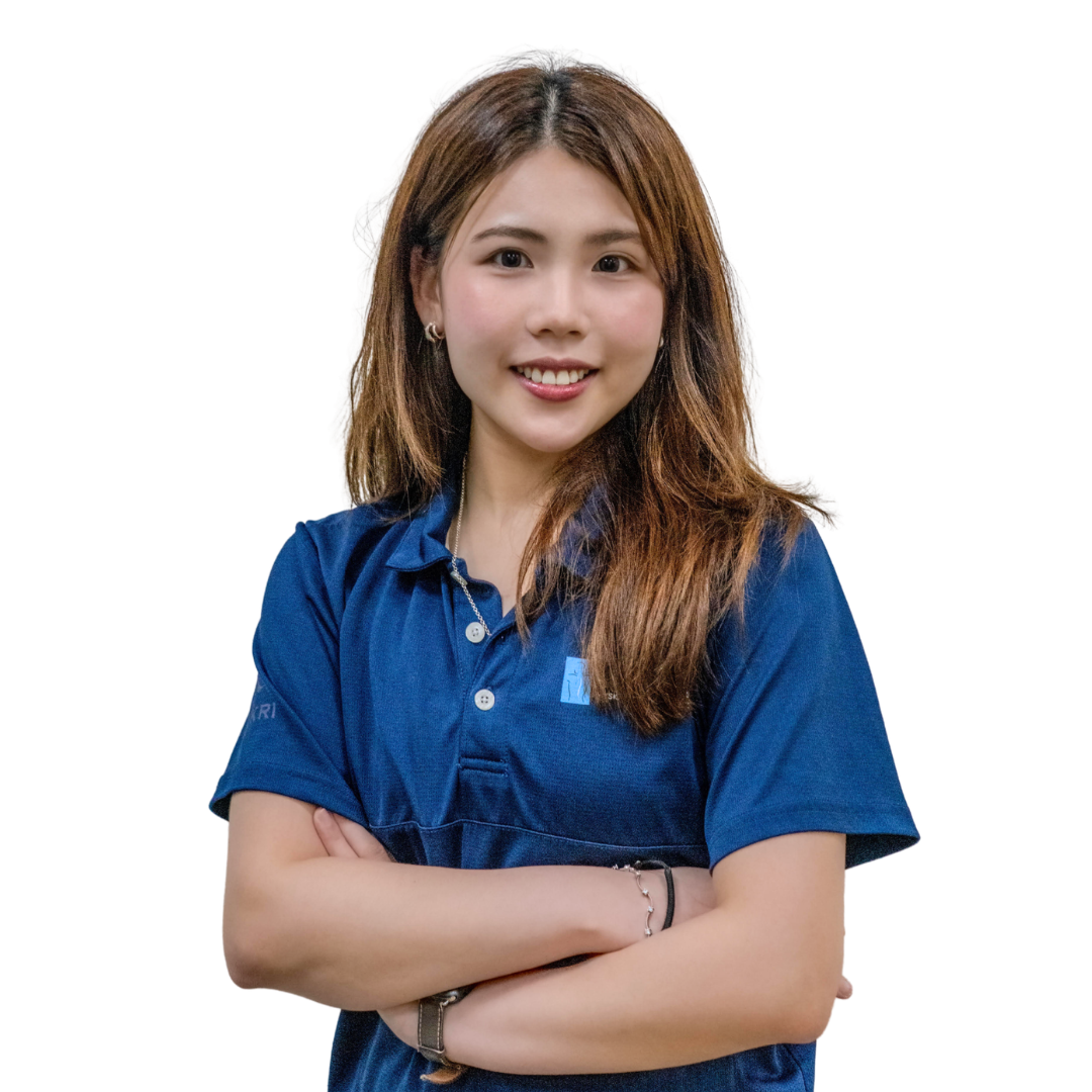 Young woman with shoulder-length brown hair, smiling, wearing a blue polo shirt, arms crossed, against a white background.