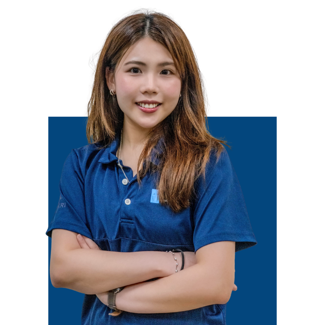 一位留著長棕髮的年輕女子面帶微笑，身穿藍色POLO衫，雙臂交叉，站在白色背景前，身後有一塊藍色長方形。