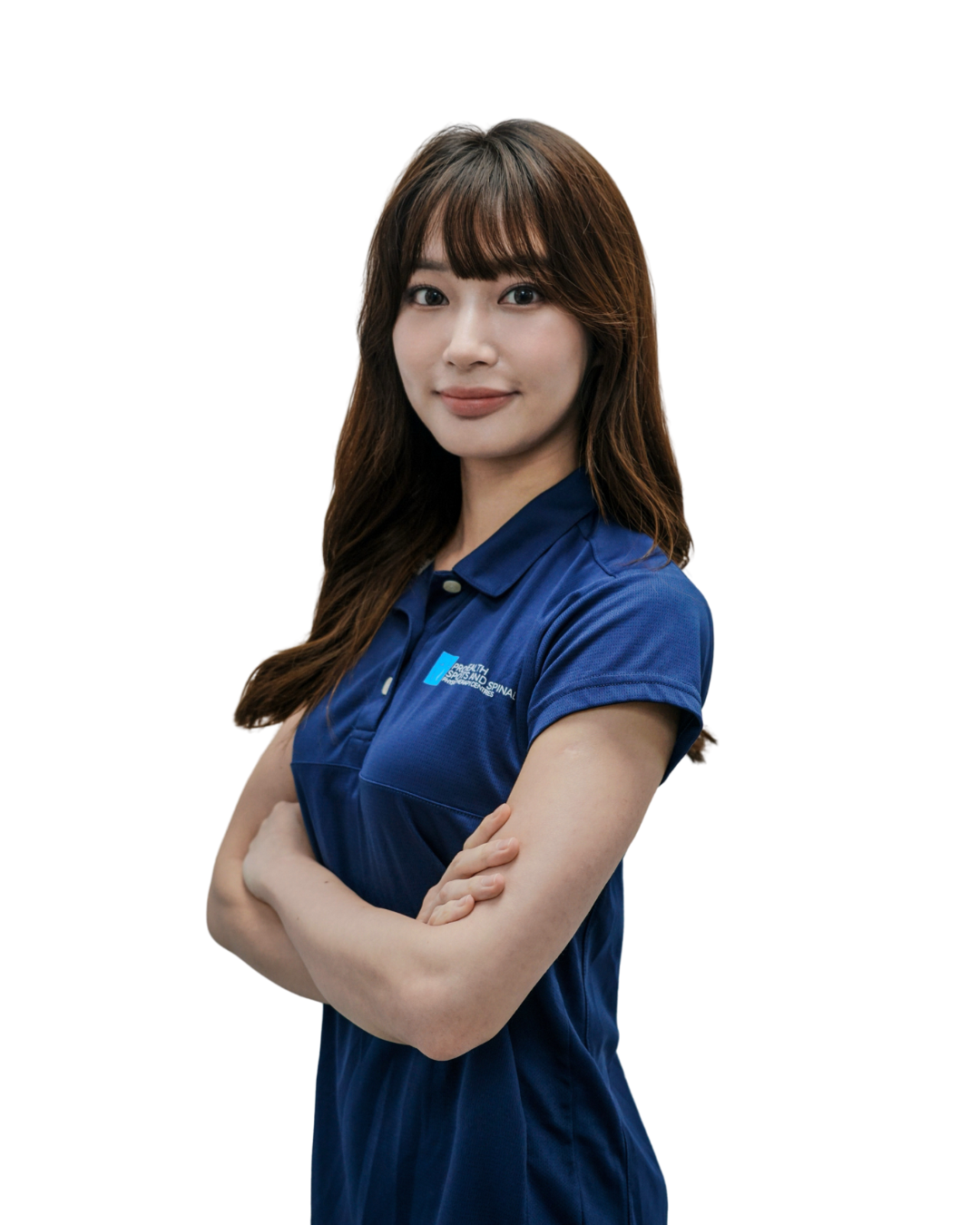 Young woman with dark hair wearing a blue polo shirt, arms crossed, smiling, standing against a white background.