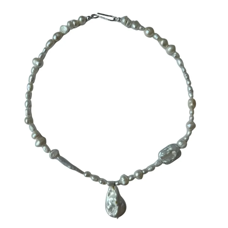 Pearl necklace with a large pendant, made of irregularly shaped pearls, on a white background.