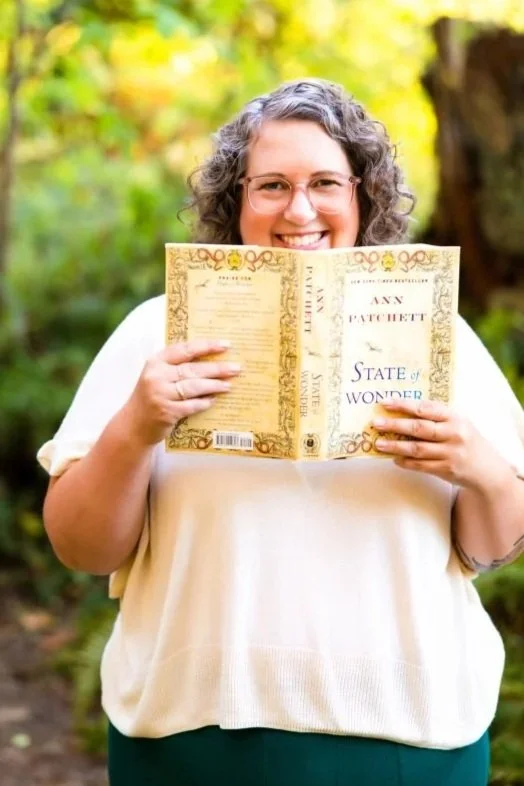 Annie Mesaros smiling while holding a book outdoors.