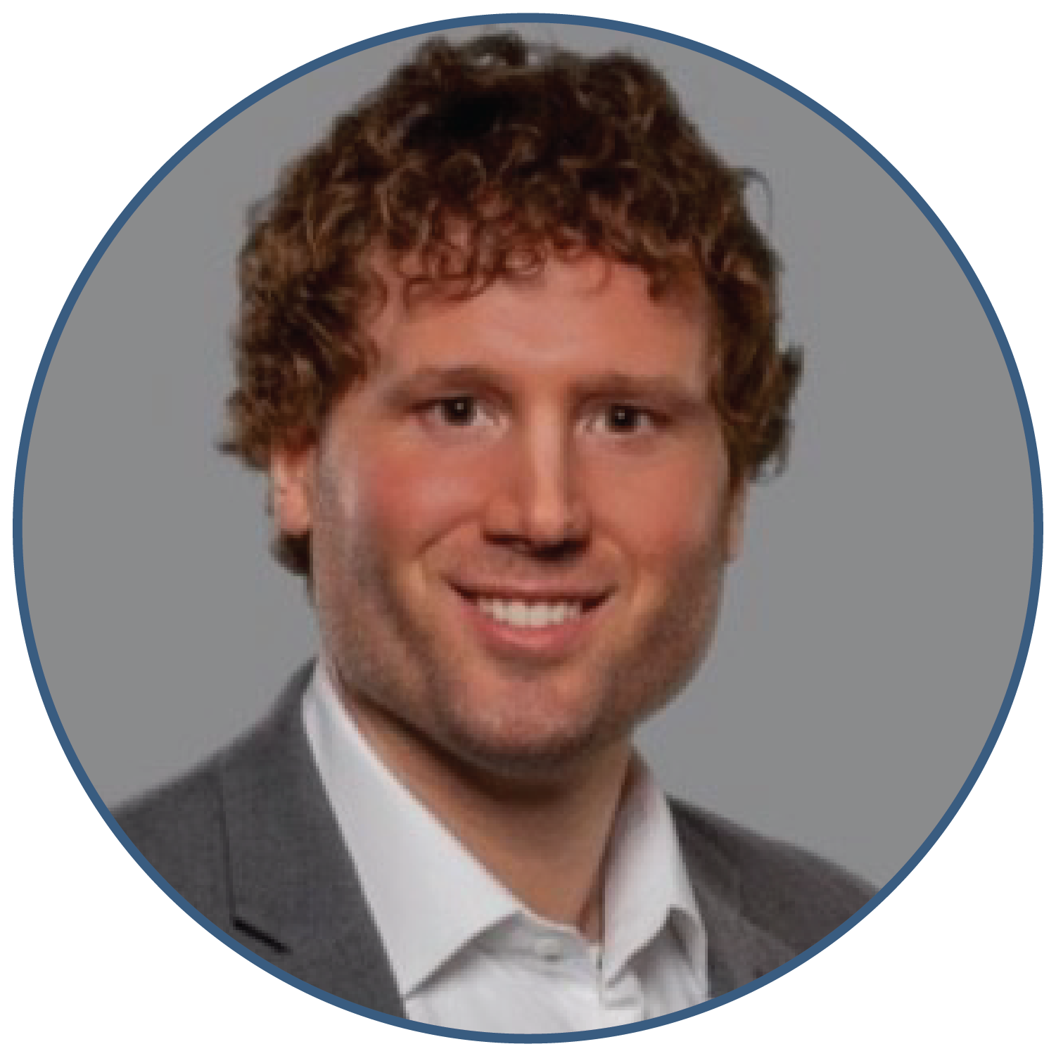 Portrait of a person with curly hair in a suit against a gray background.