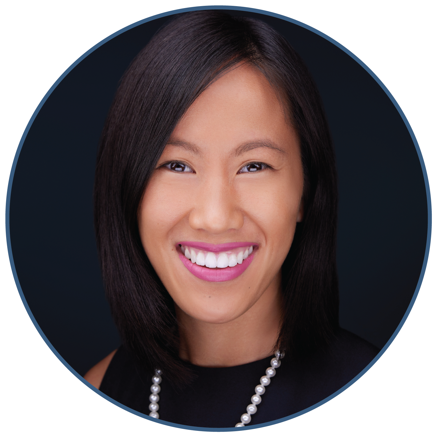 Portrait of a woman smiling with straight hair and wearing a necklace against a dark background.