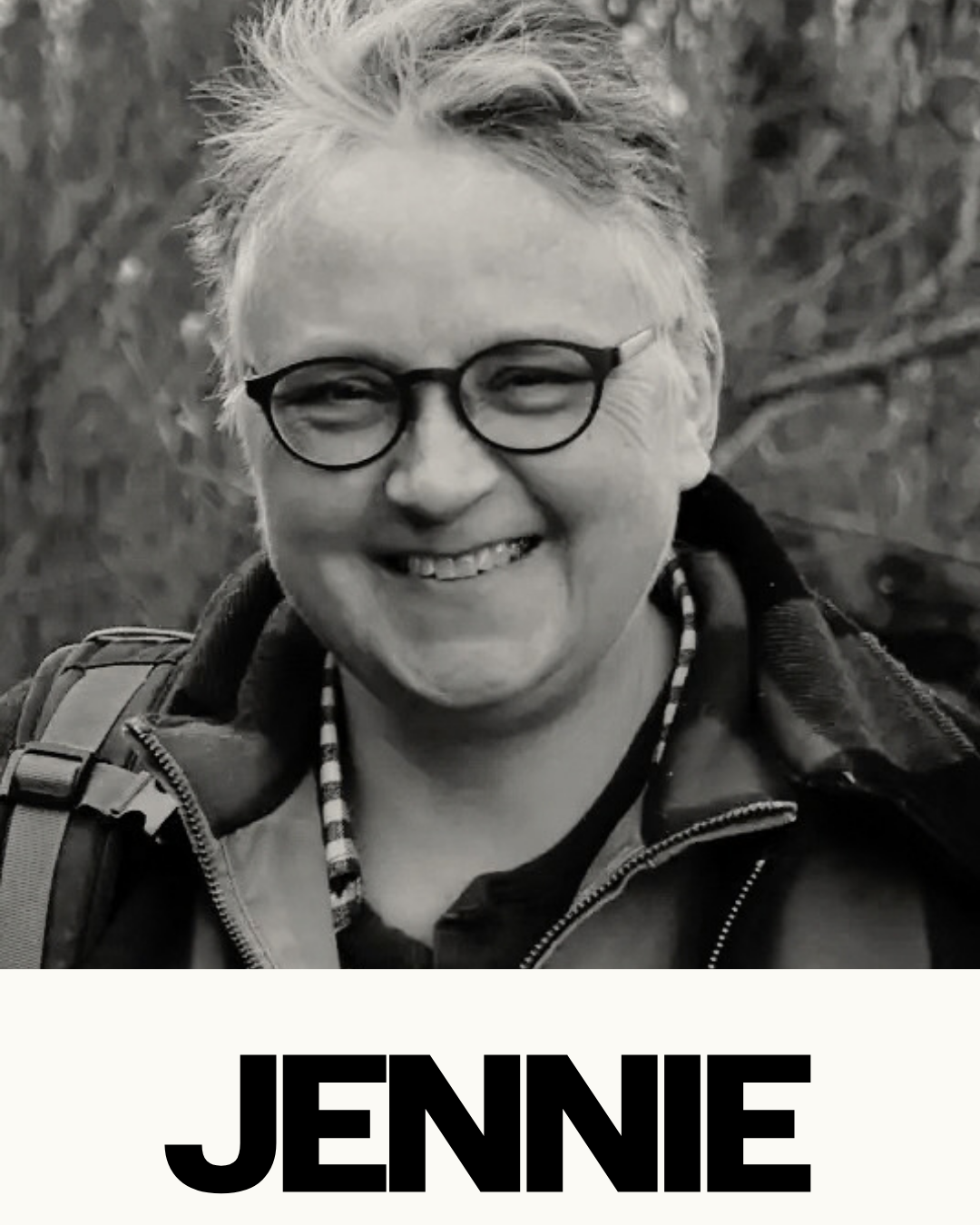 A smiling person wearing glasses and a jacket outdoors, with the name "JENNIE" written at the bottom.