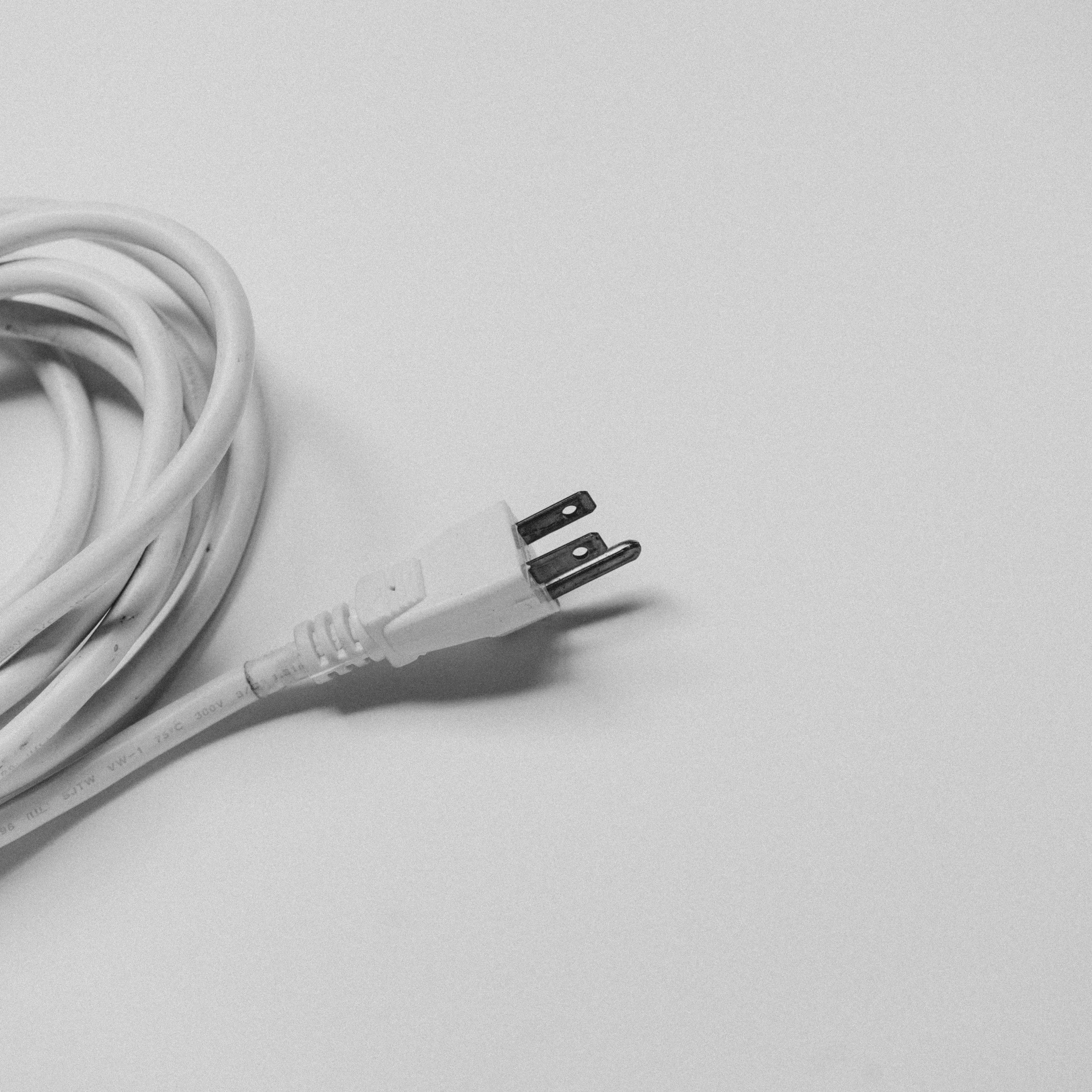 A coiled white electrical cord with a two-prong plug, styled like a Squarespace maintenance Toronto workspace.