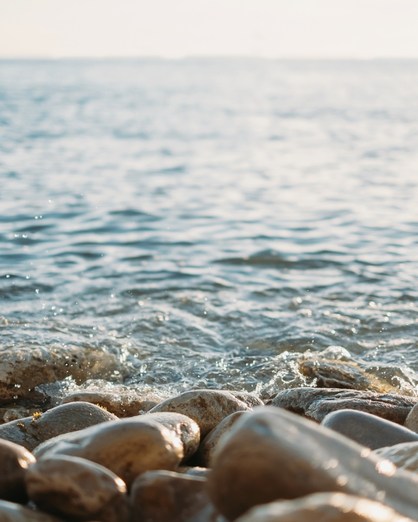 Rocks by the shore of the ocean where they meet the water.