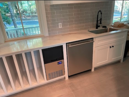 Modern kitchen with white cabinetry, built-in wine rack, dishwasher, ice maker, and black faucet.
