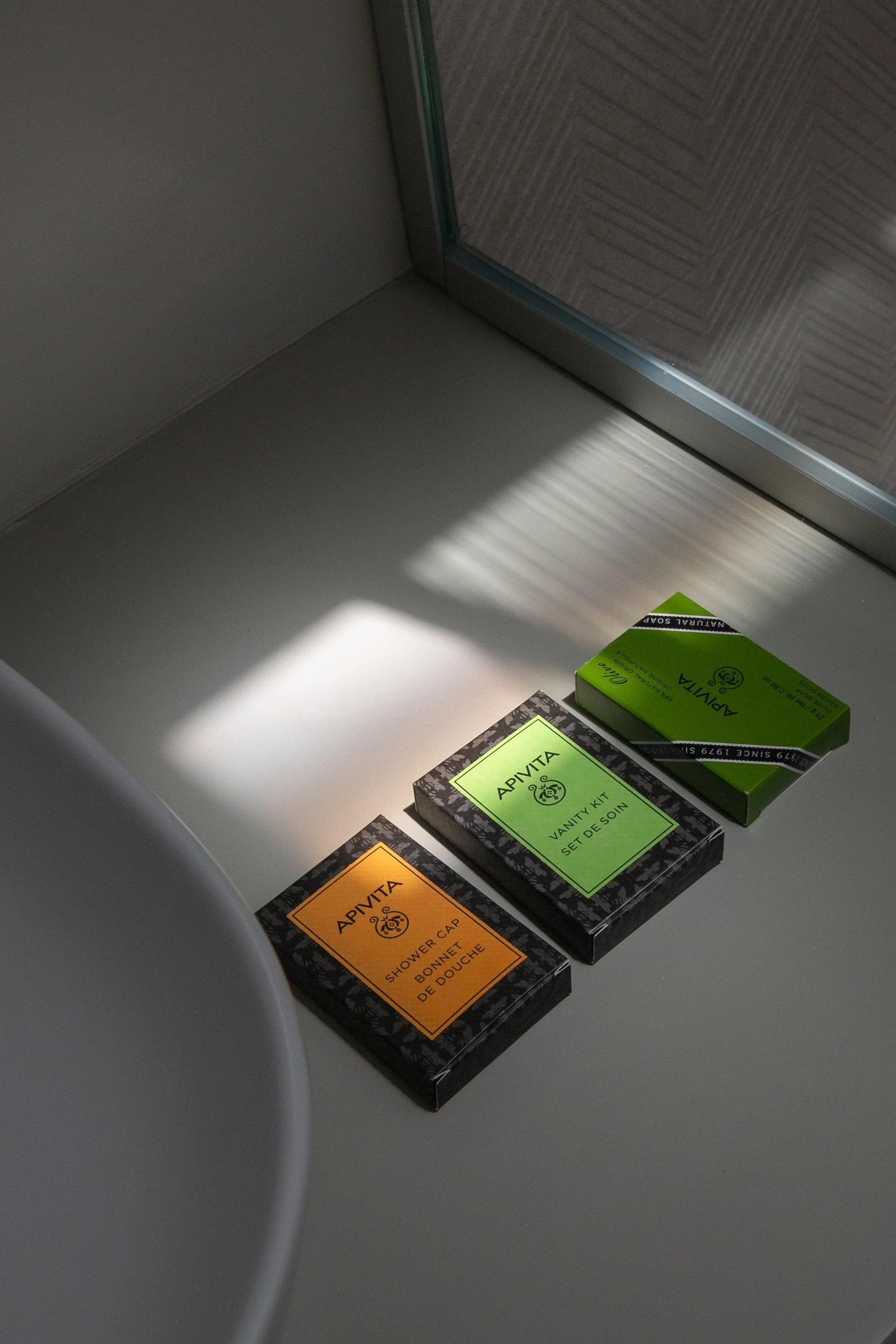 Three boxes of Aromita toiletries on a white surface near a window, with sunlight casting shadows.