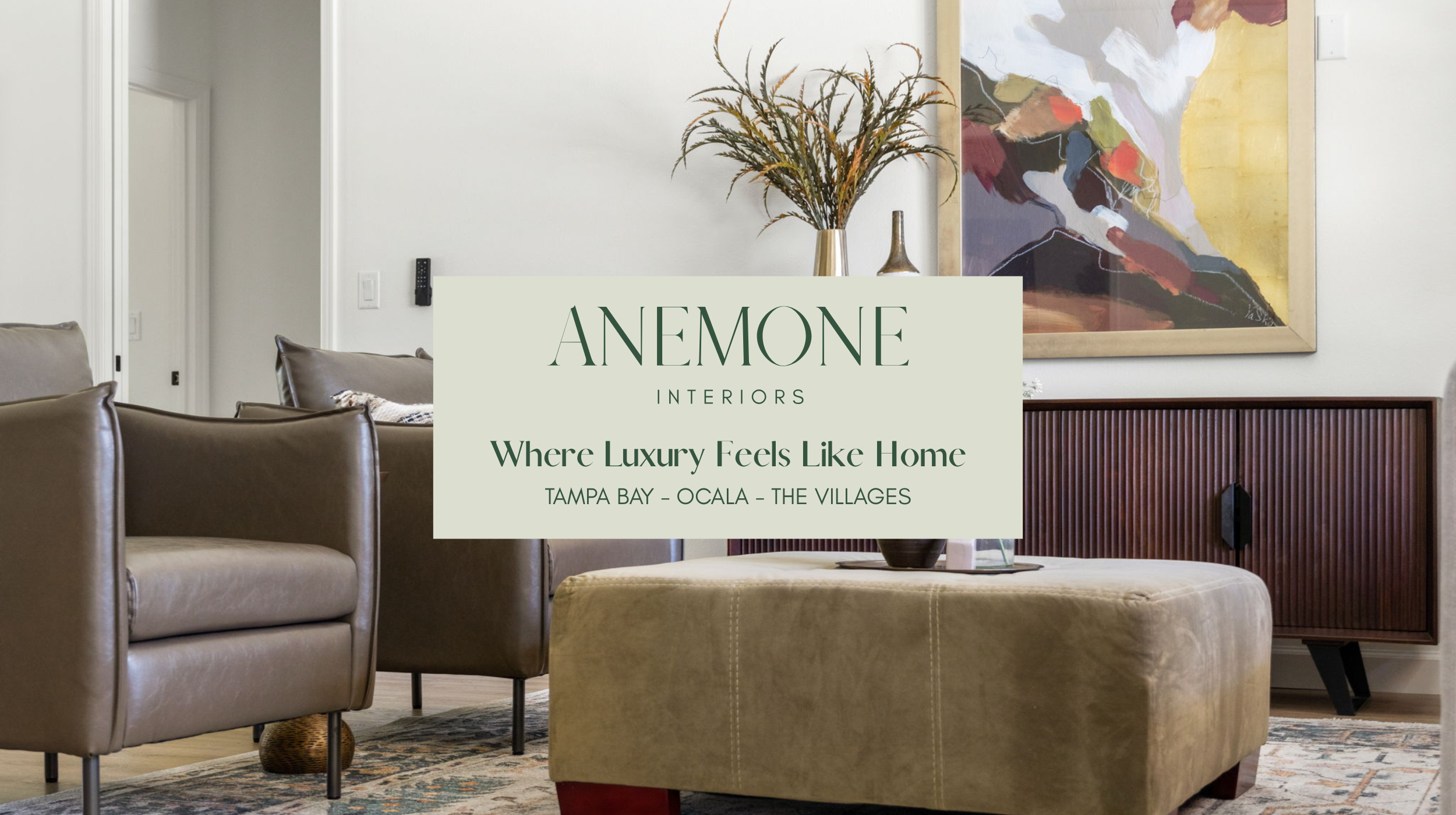 Contemporary living room by Anemone Interiors featuring rich leather seating, fluted wood media cabinet, abstract artwork, and layered textures for a warm livable luxury aesthetic.