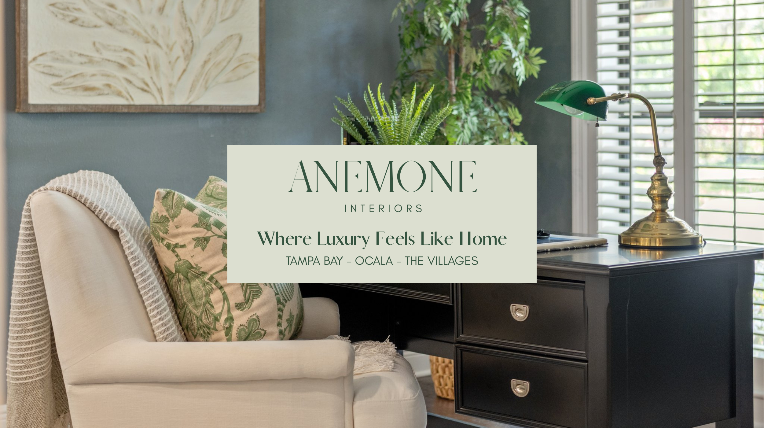 Moody home office and reading nook designed by Anemone Interiors with dark charcoal walls, botanical accents, brass lighting, and cozy layered textures for a sophisticated Florida workspace.