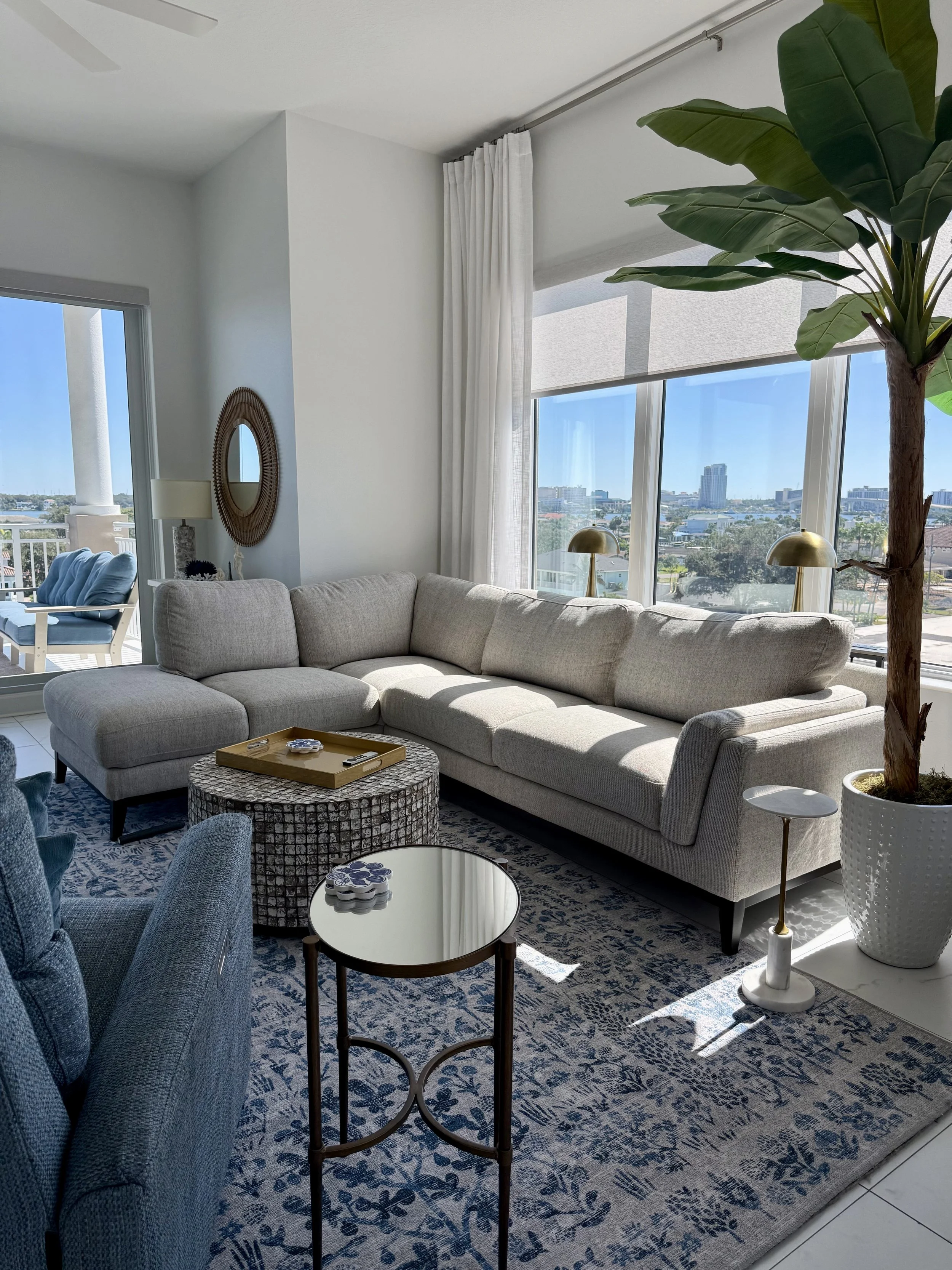 Waterfront condo living room designed in a mid-century coastal style with layered blues, warm neutrals, and expansive Clearwater Beach views.