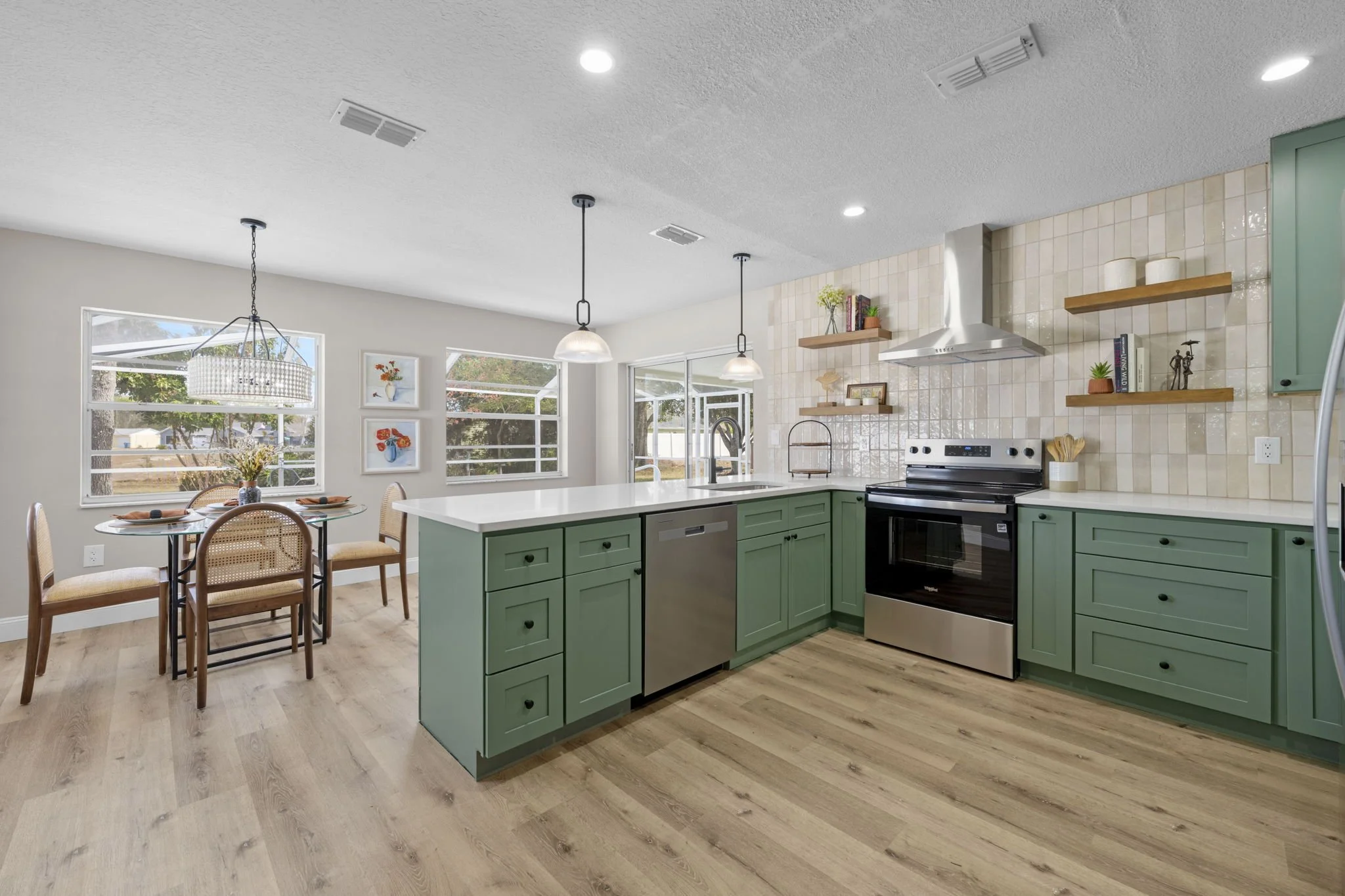 Completed kitchen renovation for Dothan Revival featuring sage green cabinetry, open shelving, warm wood flooring, and an expanded layout designed for improved storage and functionality.