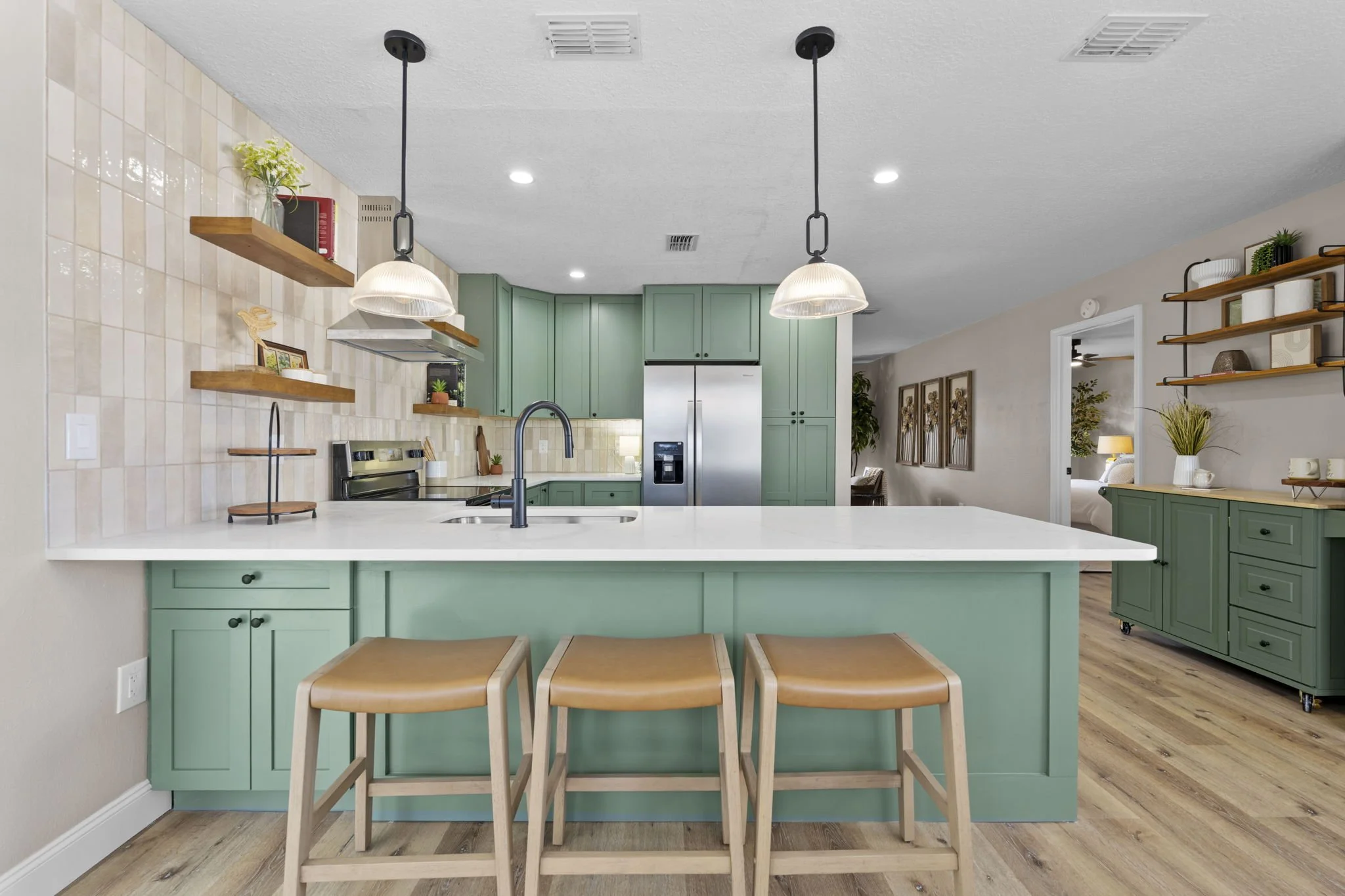 Interior kitchen redesign featuring custom green cabinetry, quartz countertops, open shelving, and an improved floorplan to maximize storage and create a more open living experience.