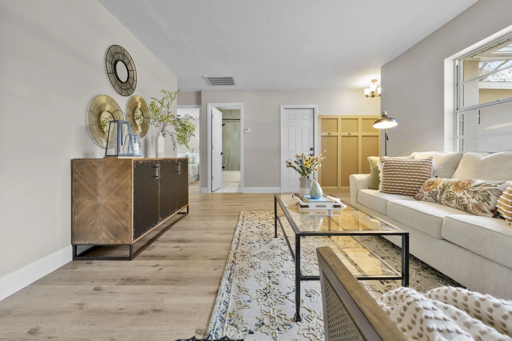 Living room interior design for Dothan Revival featuring layered neutrals, warm wood finishes, custom entry detailing, and an updated open concept layout.