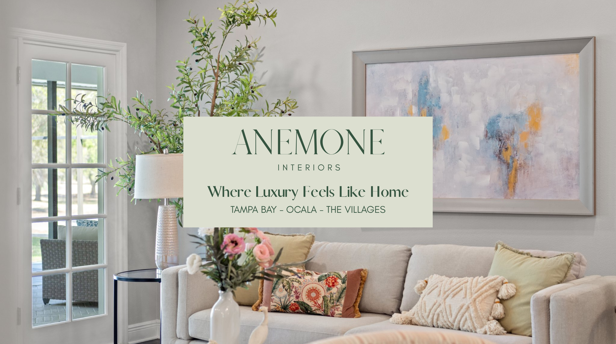 Bright transitional sitting room by Anemone Interiors featuring soft neutral seating, oversized abstract artwork, fresh florals, and airy natural light in a refined Tampa Bay home.