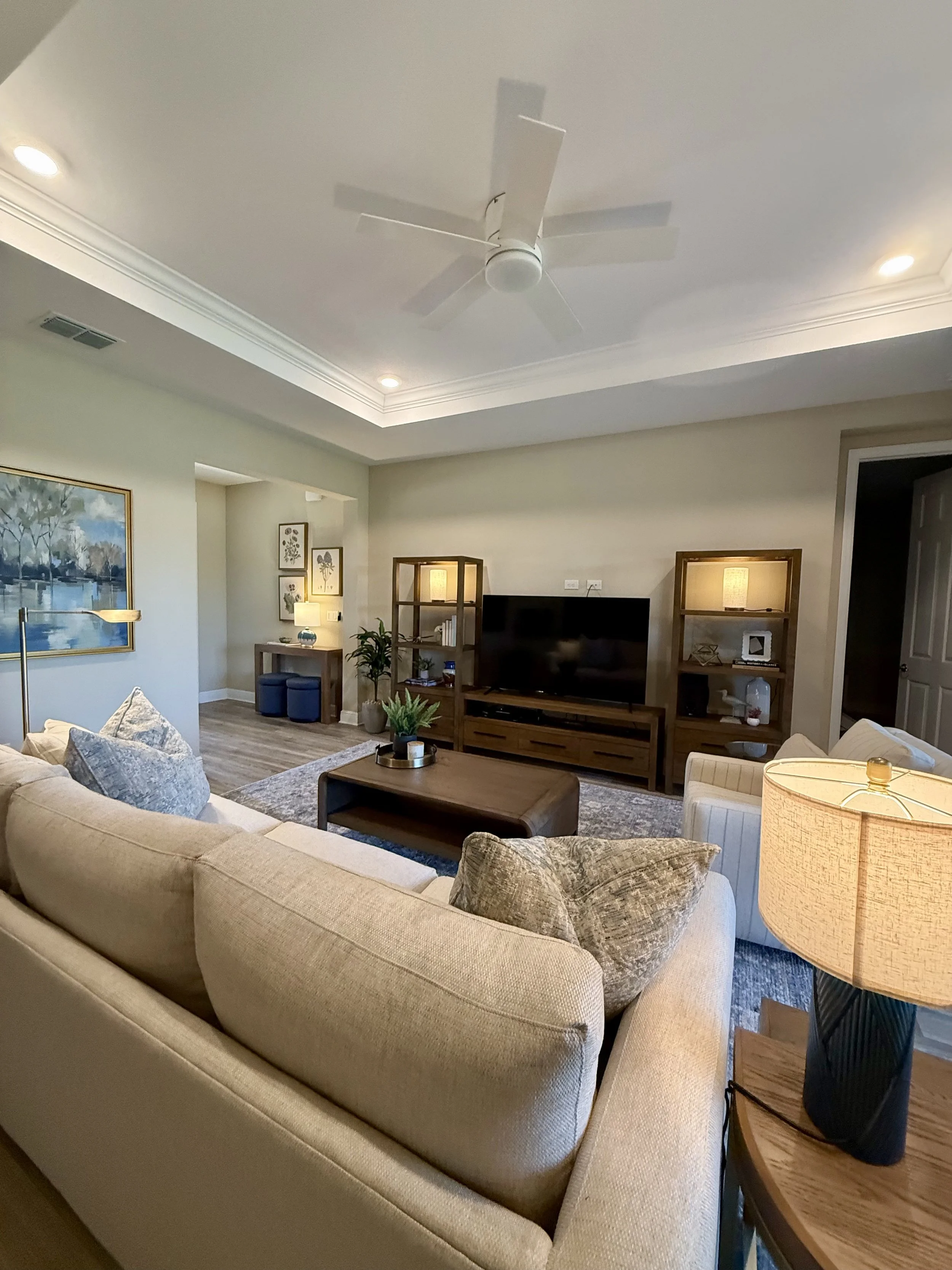 Warm and inviting family room designed for an elderly couple in Ocala, Florida featuring soft neutral furnishings, warm wood tones, layered lighting, and comfortable seating for everyday living.