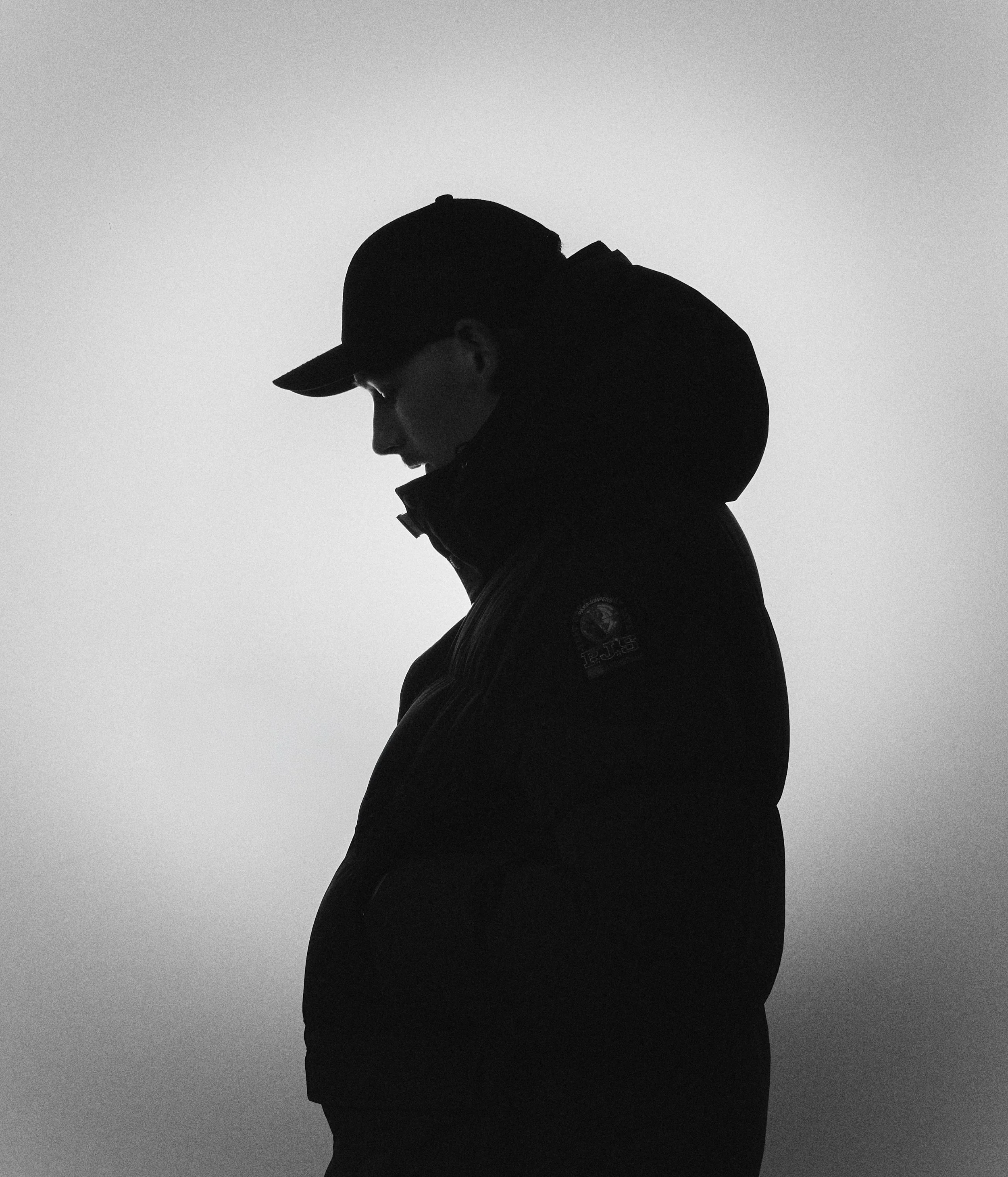 Mand med solbriller ser op mod himlen, baggrund af blå og hvide skyer.