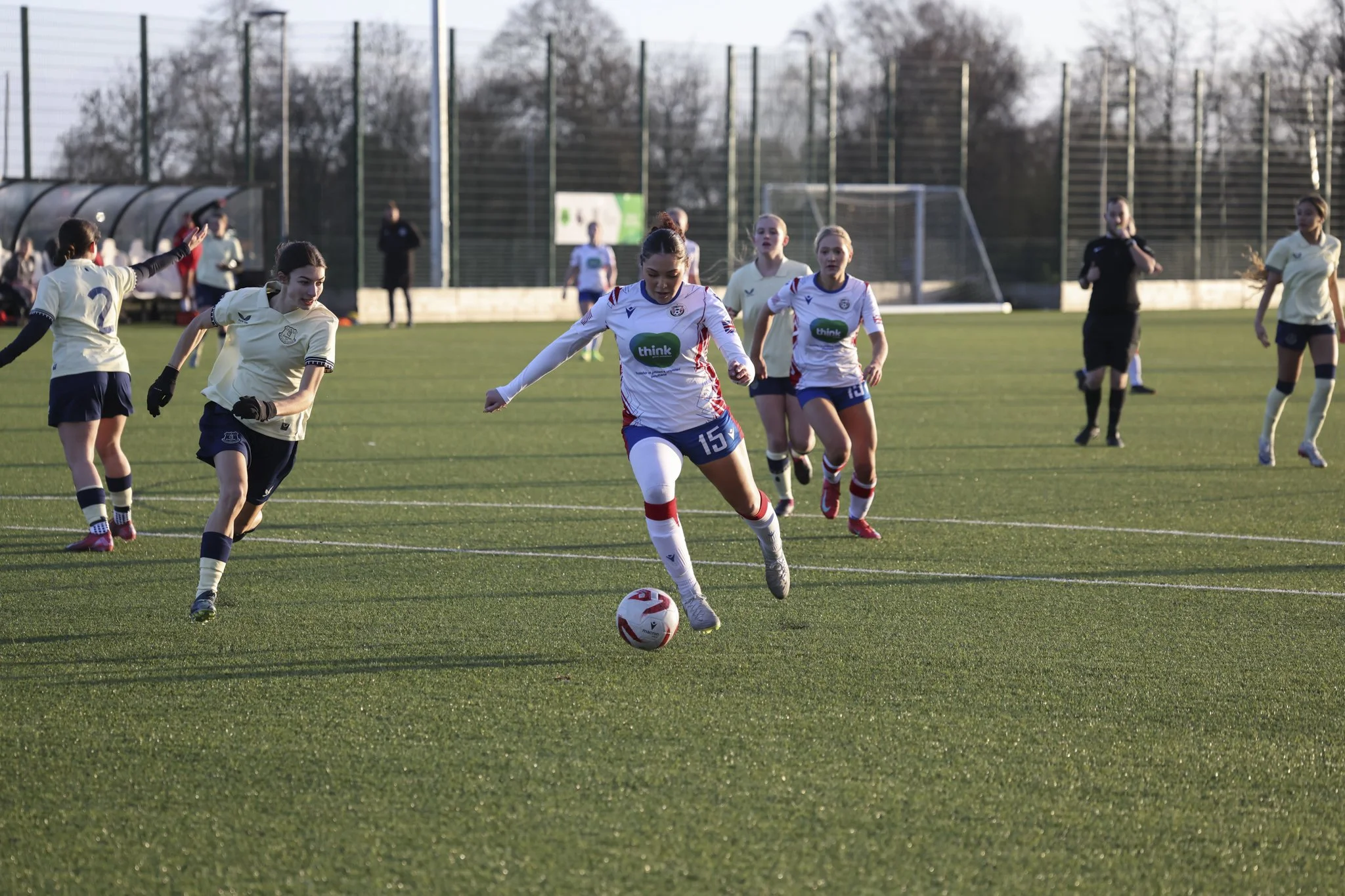 Soccer game with female players on a field, focusing on player wearing jersey number 15 about to kick the ball.