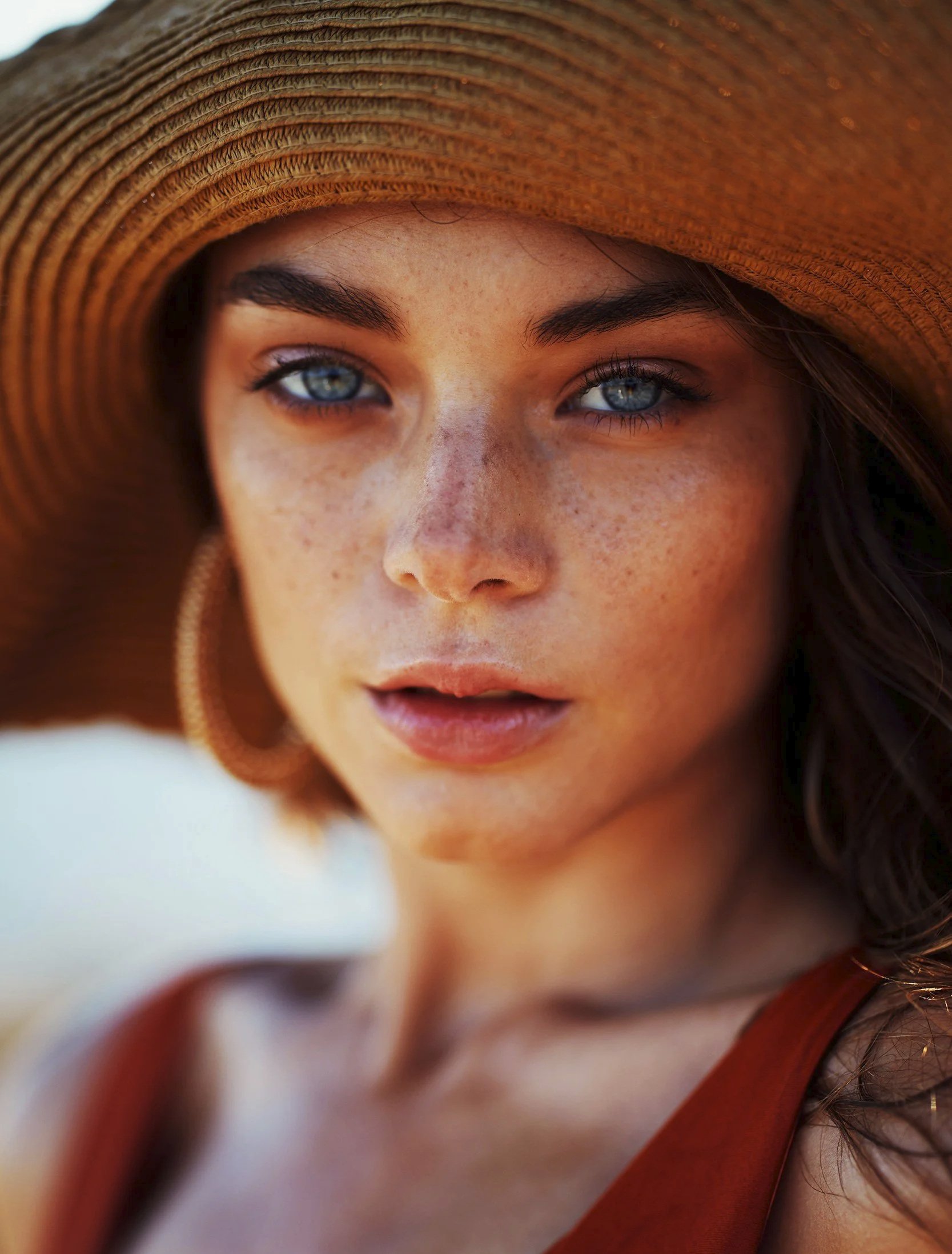 Woman with glowing sun-kissed skin wearing a summer hat