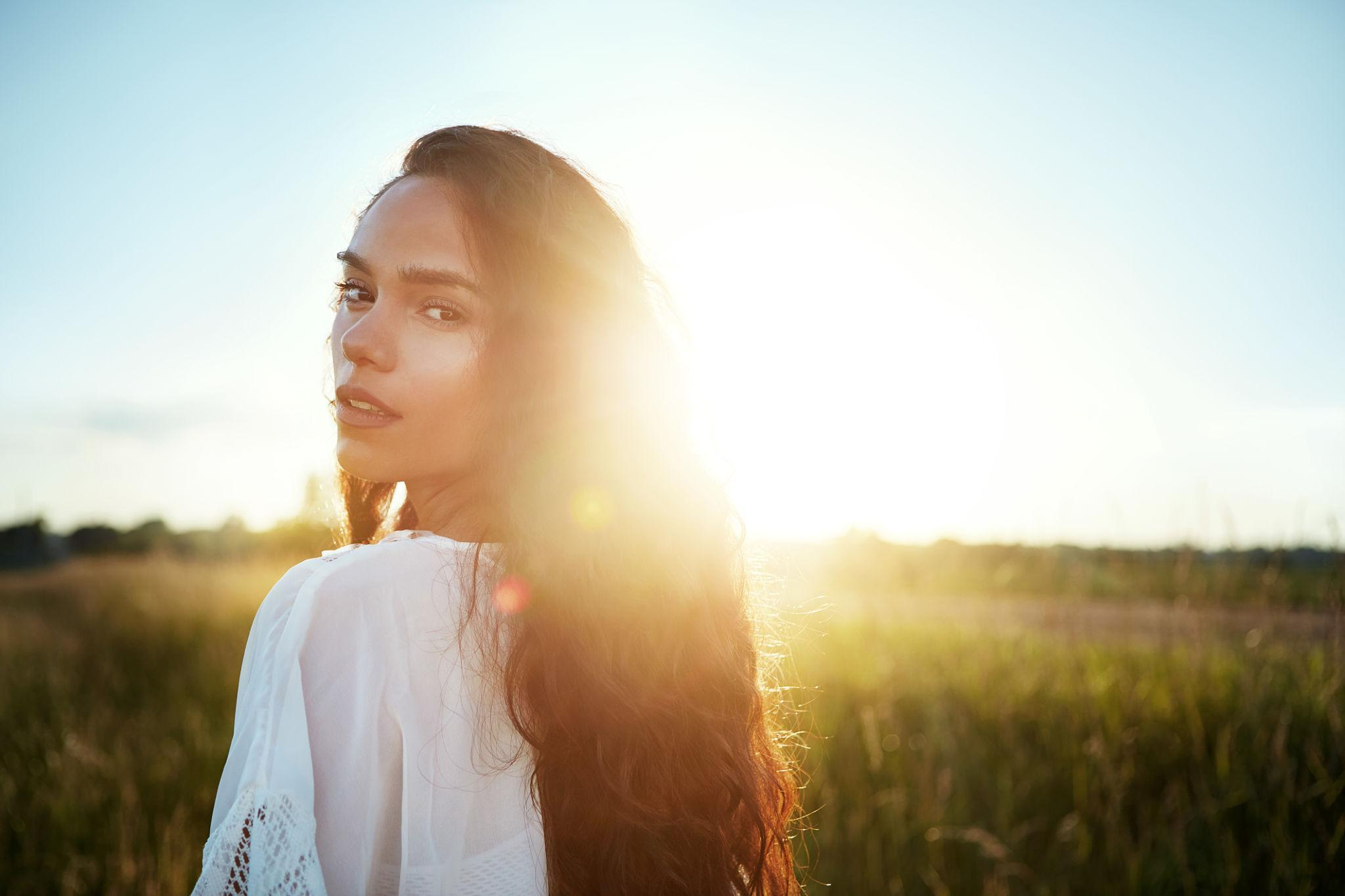 Woman with glowing skin in natural sunlight, fresh spring beauty look