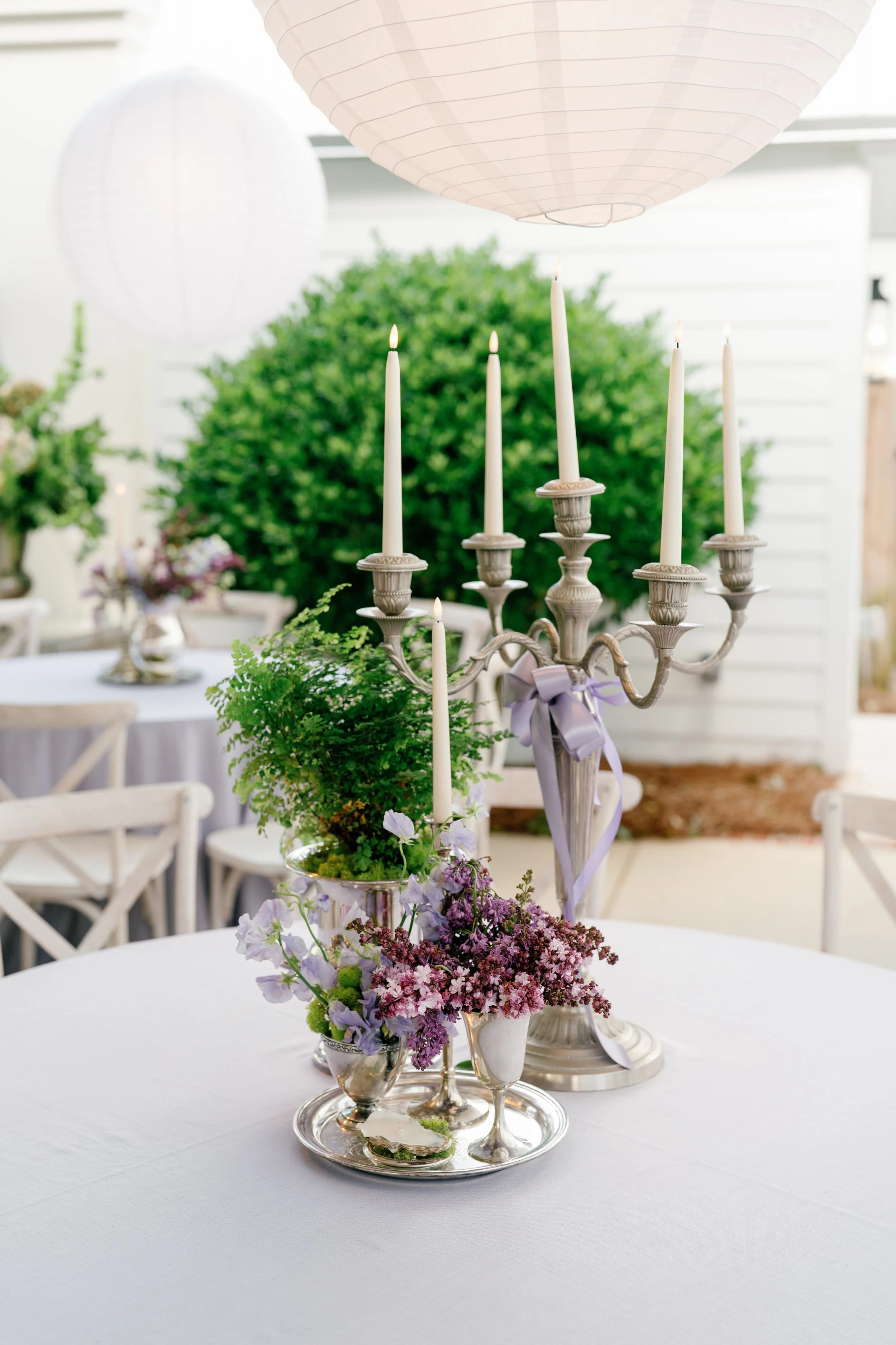 Decorative table centerpiece with silver candelabrum, candles, and flowers, part of a wedding or event setup.