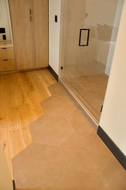 Hexagon brown tile floor blend in with wood floors outside tile shower