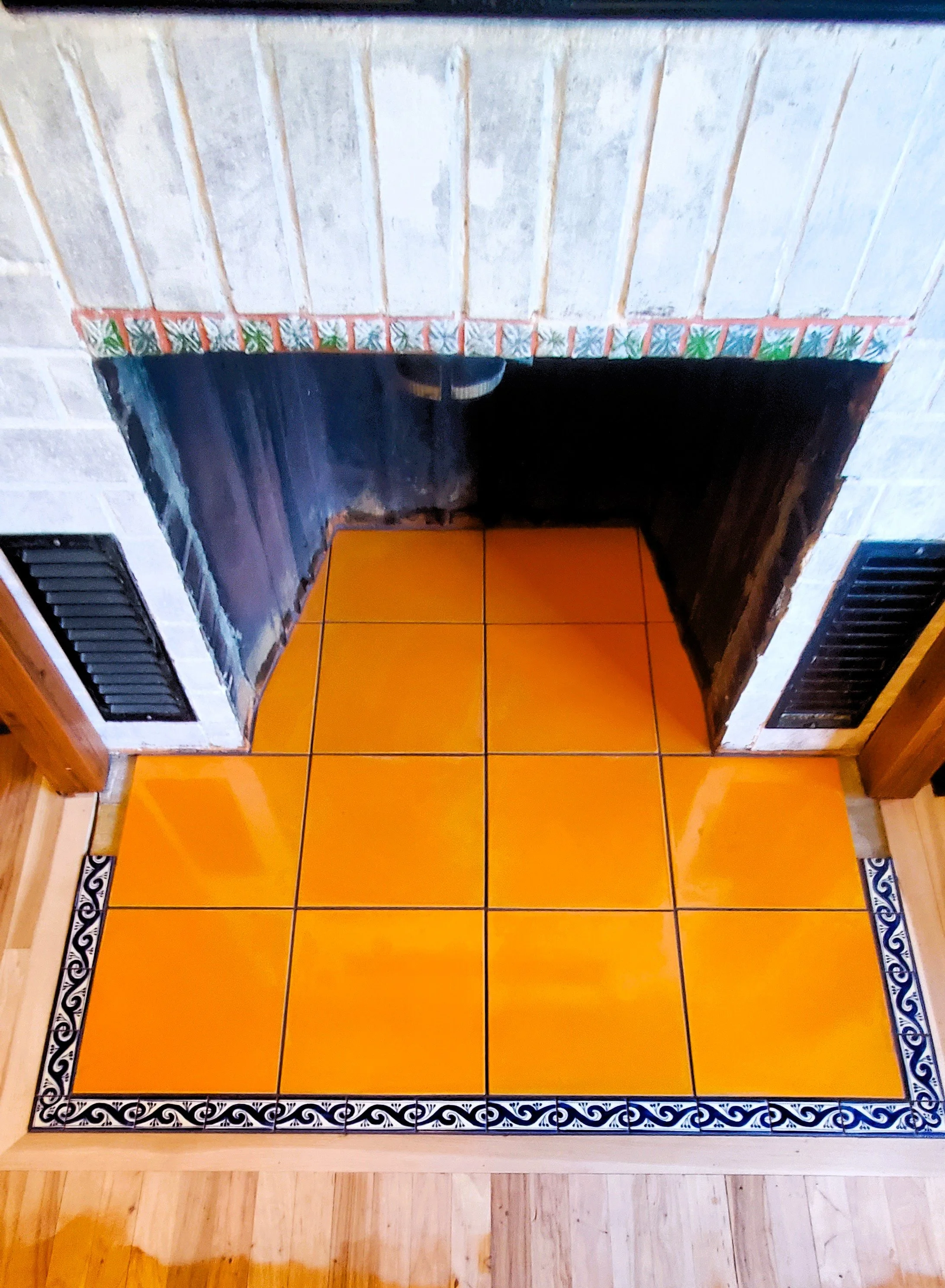 Orange tile with blue detail tile fireplace