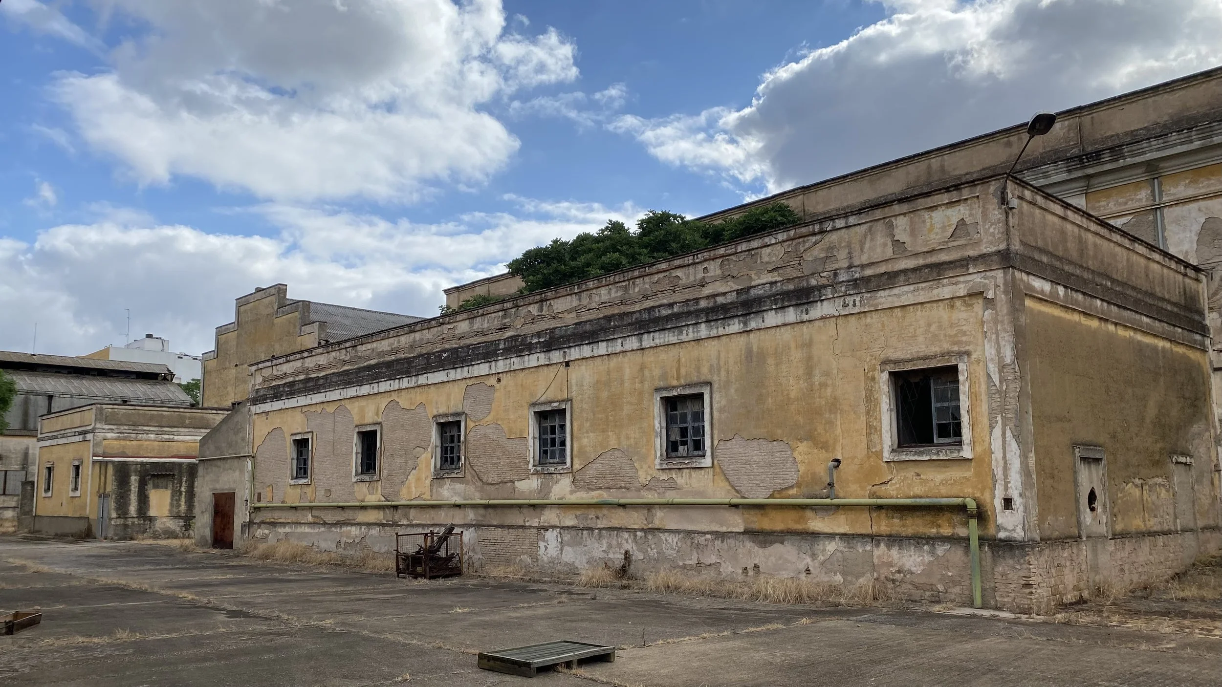 Edificio viejo en mal estado con paredes desgastadas y ventanas rotas bajo un cielo nublado