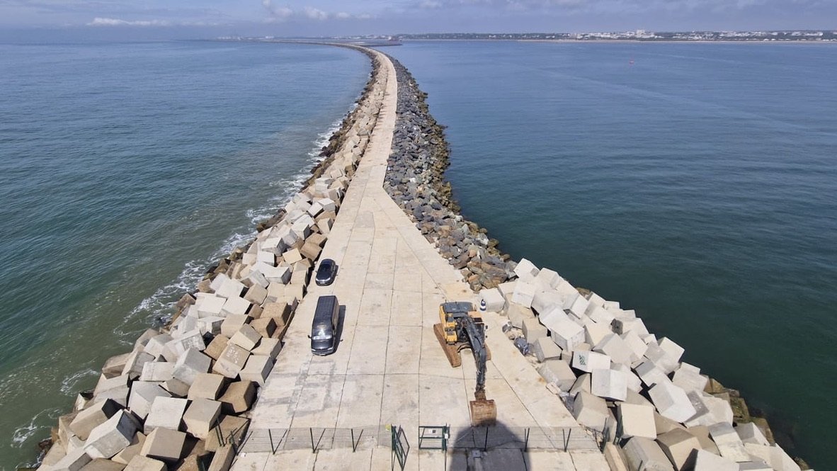 Barra de defensa en el mar en construcción con vehículos y maquinaria.