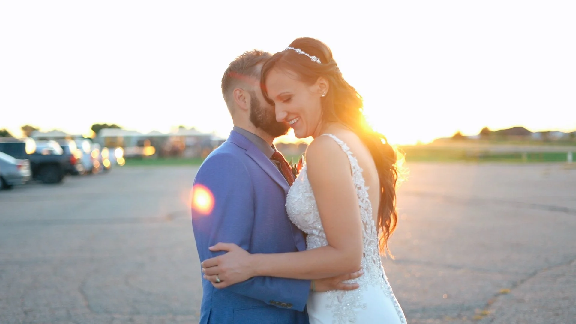 bride and groom smiling and hugging at sunset