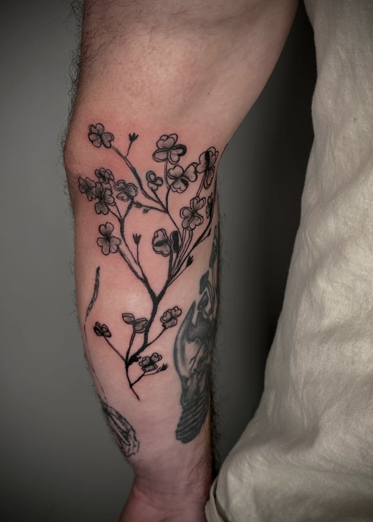 Tattoo eines Filigran-Baums mit kleinen Blüten auf dem Unterarm.