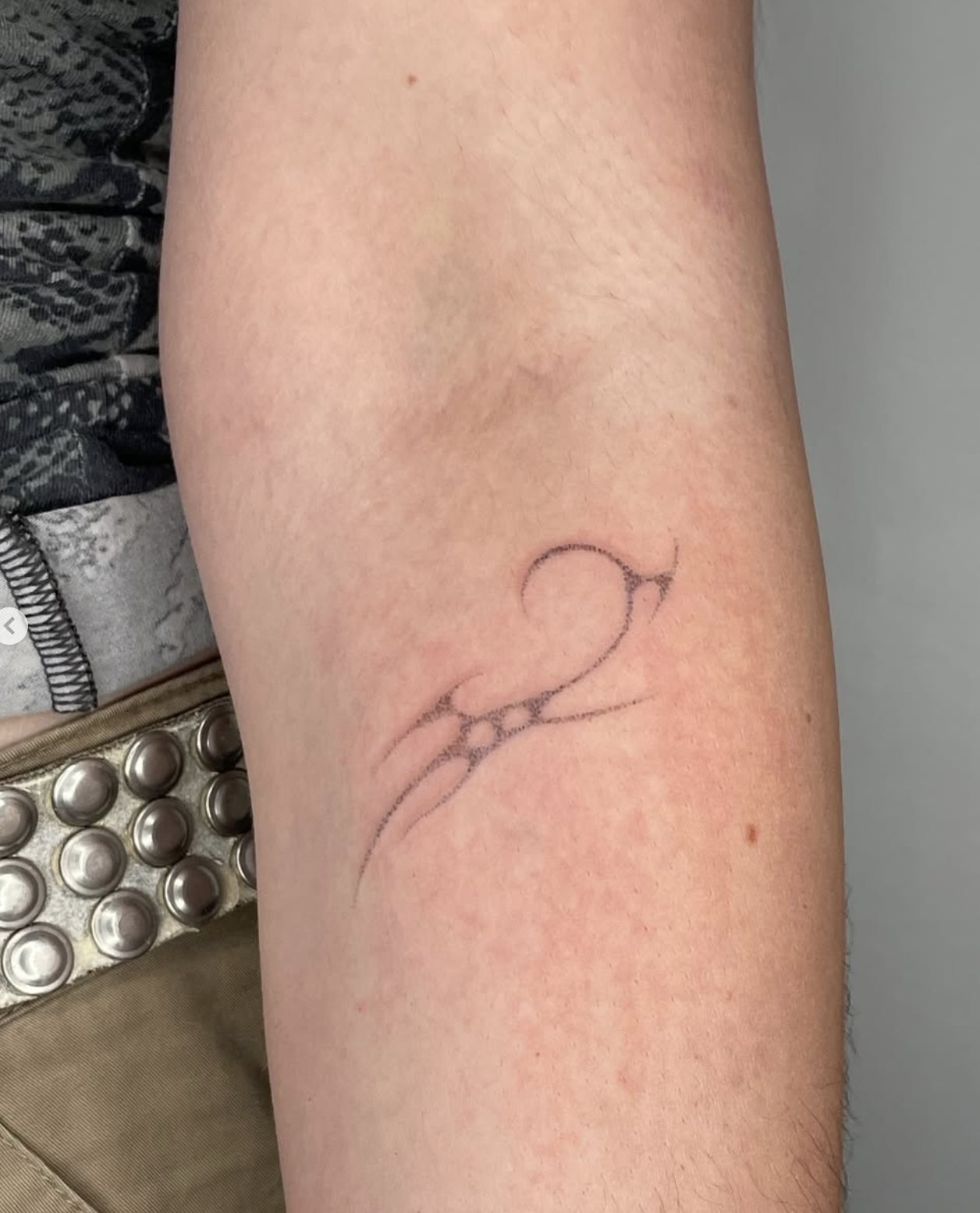 Schöner Tattoo-Schriftzug auf einem Unterarm, daneben sind Medikamente in einer Blisterpackung sichtbar.
