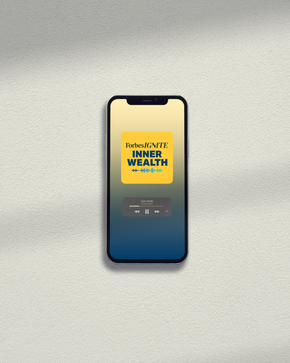 Smartphone on a wall with a podcast episode titled "Inner Wealth" playing, featuring the branding for Forbes Ignite.