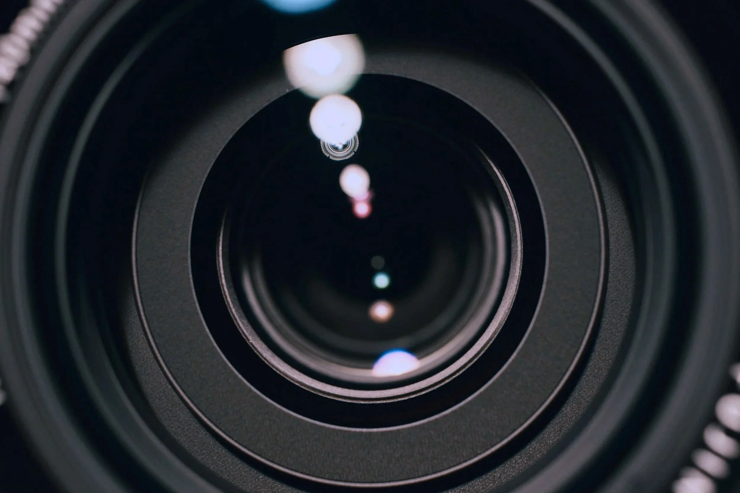 Close-up of a camera lens showing multiple concentric glass rings and reflections of light.