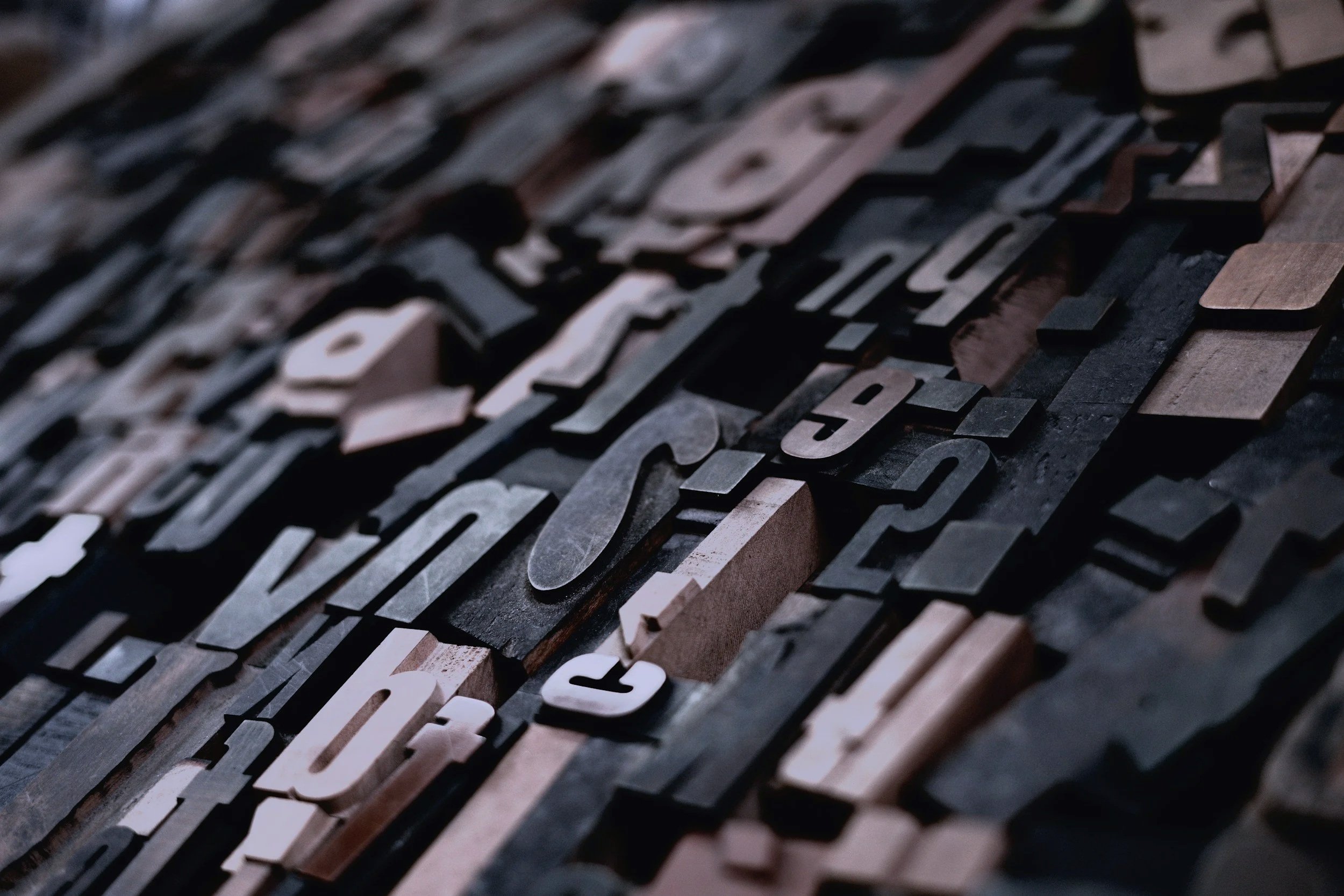 Close-up of various wooden and metal typesetting letters arranged in a pattern.