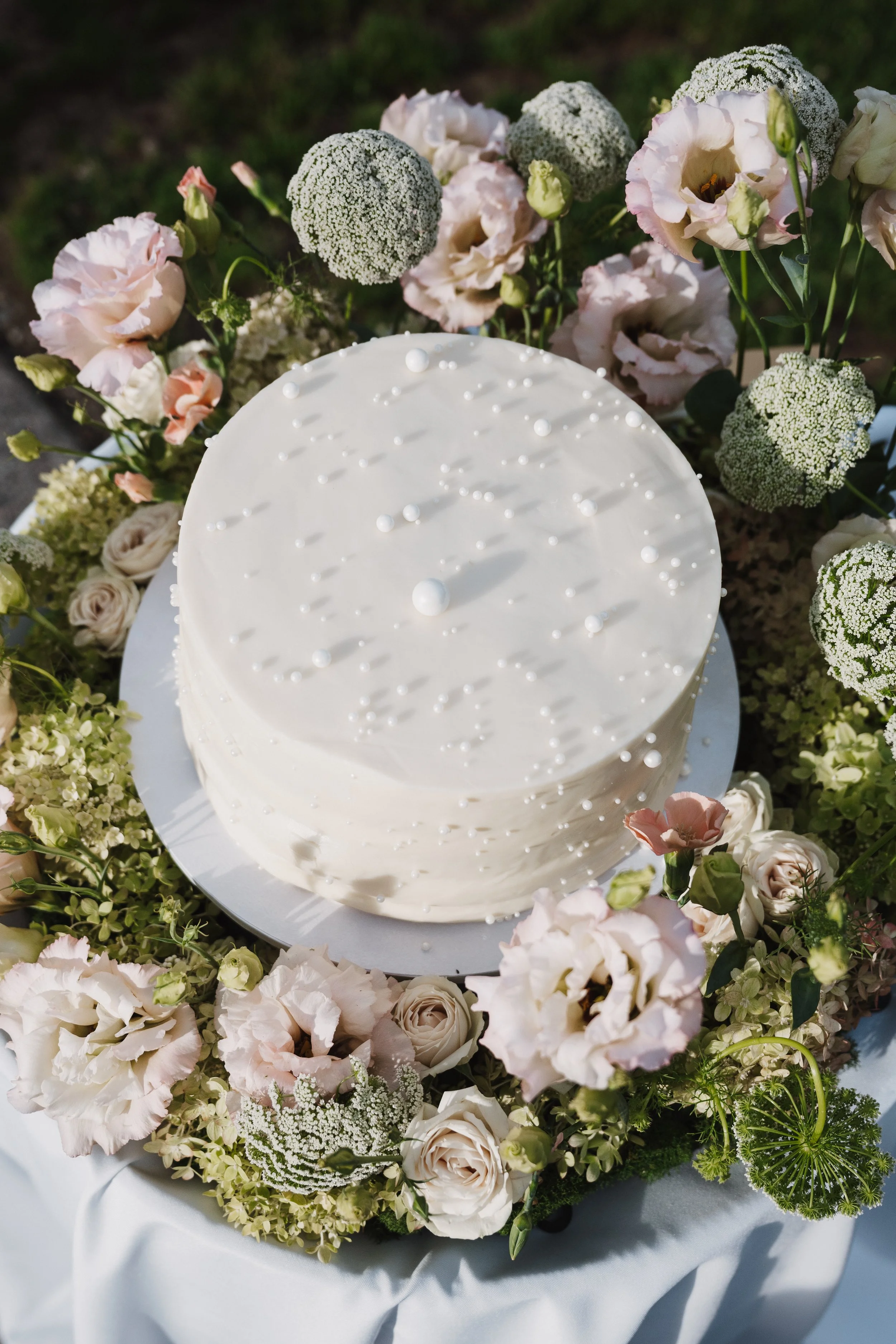Wedding cake surrounded by mauve and cream florals and lush greenery.