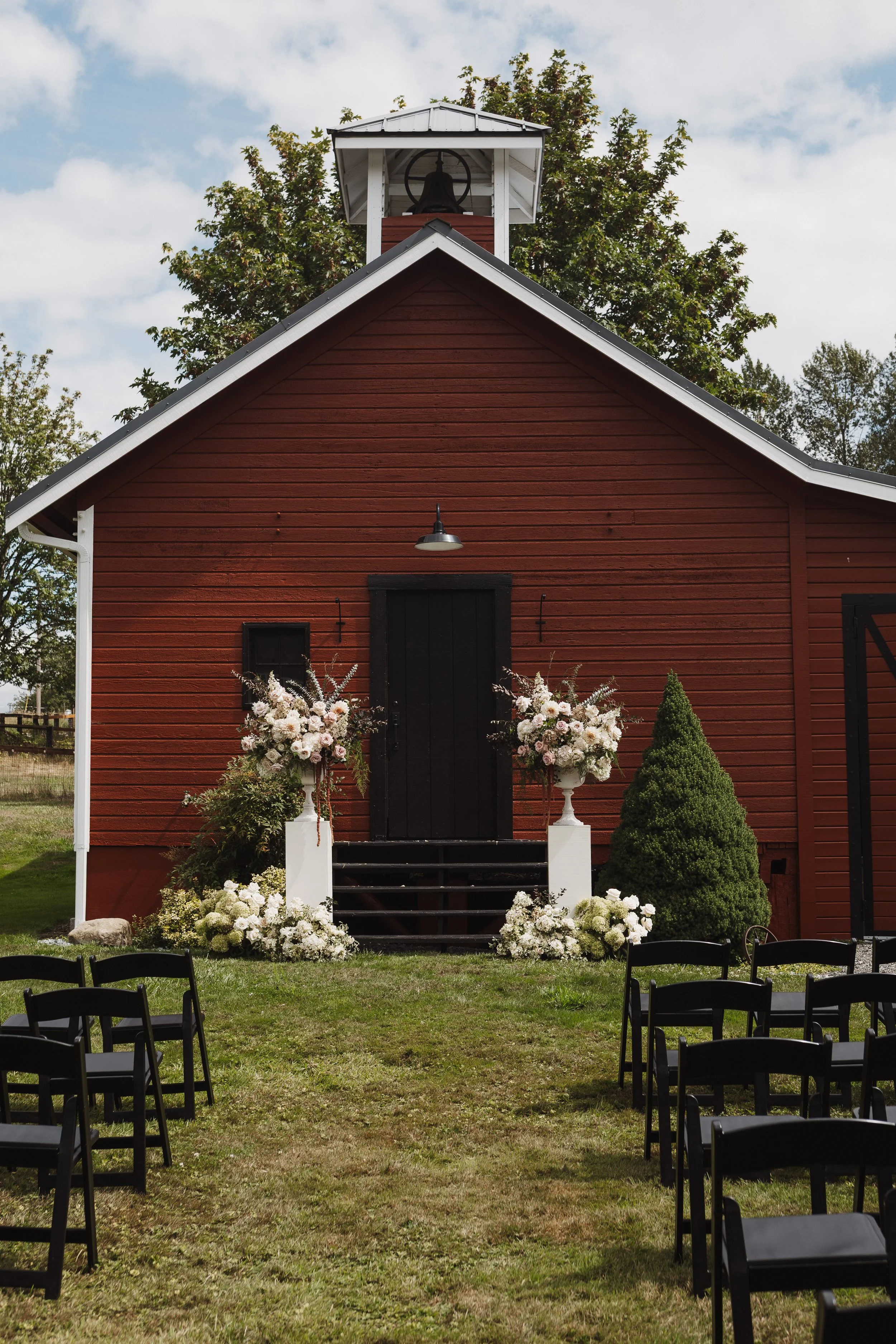 little red schoolhouse with blush and mauve floral arrangement urns flanking wedding ceremony altar.