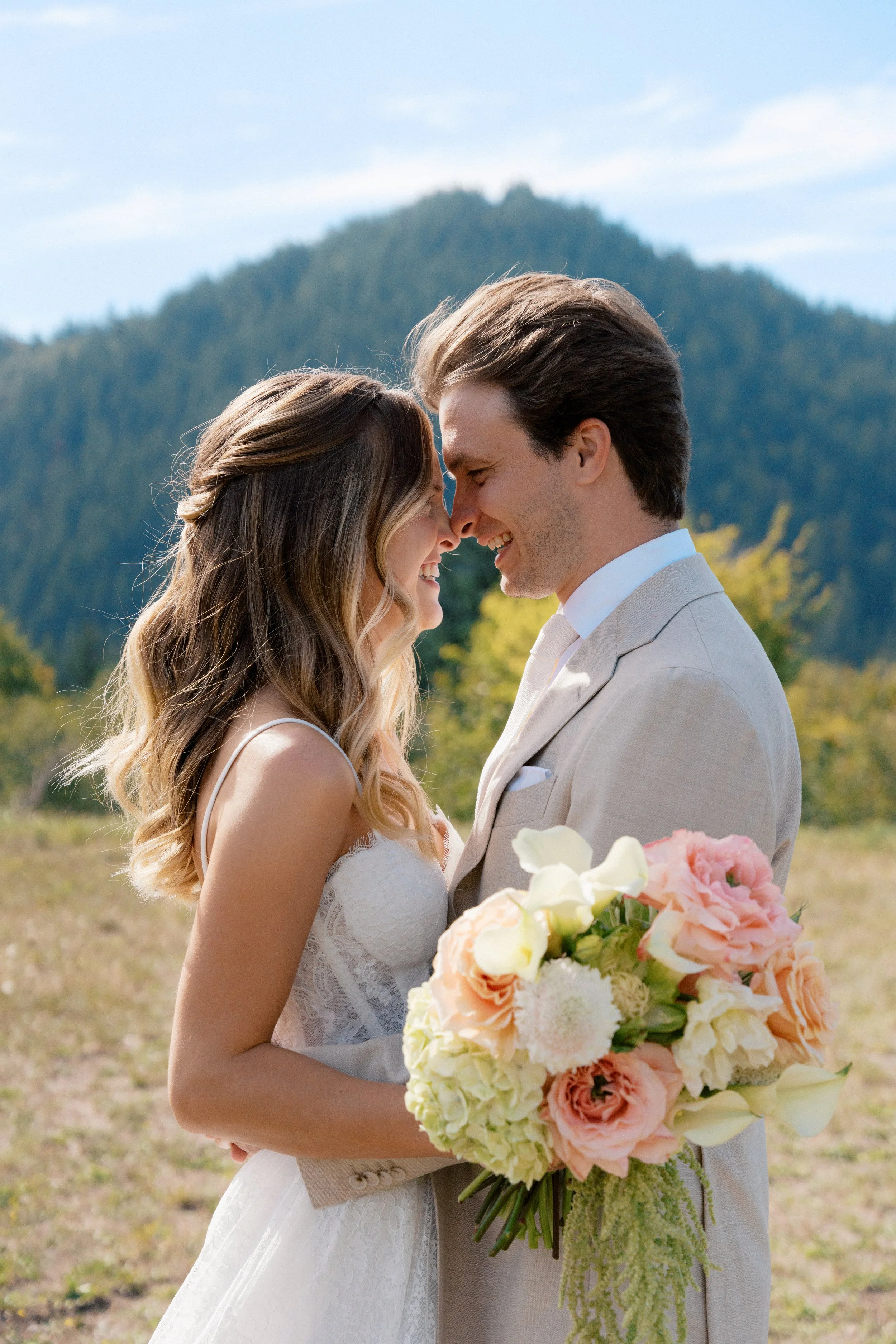 bride and groom in a mountain field with bridal bouquet