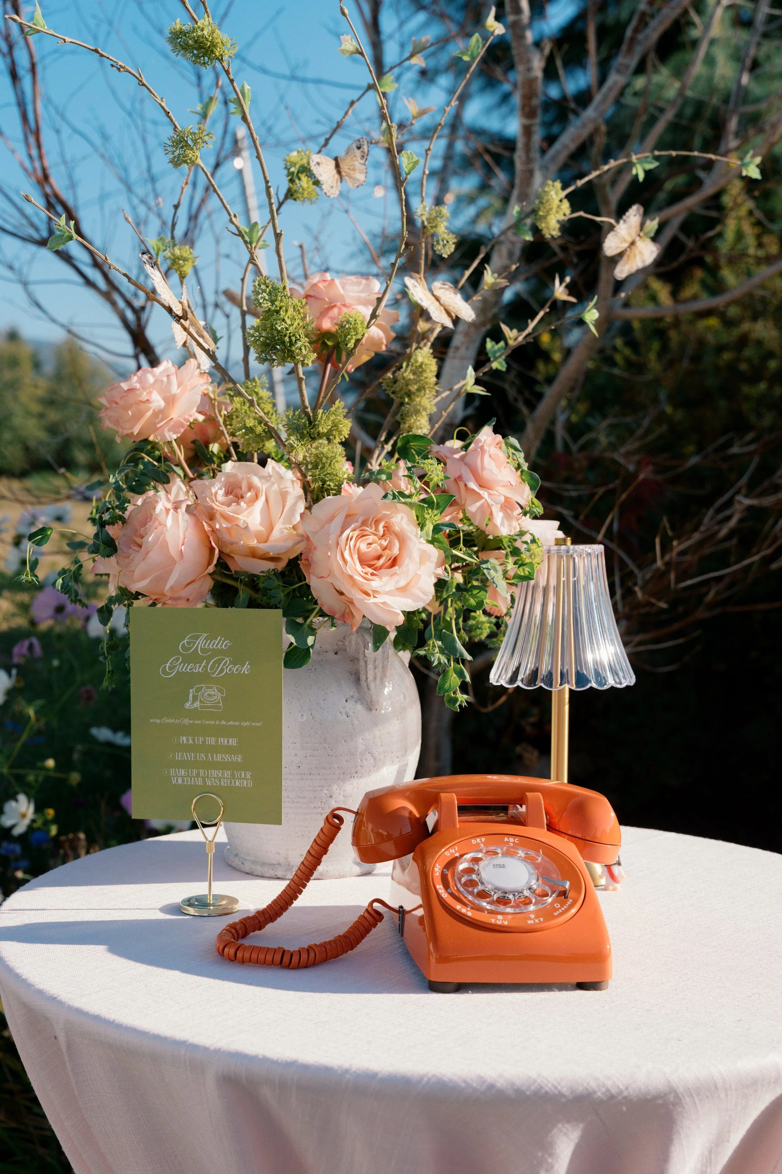 peach and chartreuse floral arrangement with an orange vintage telephone.