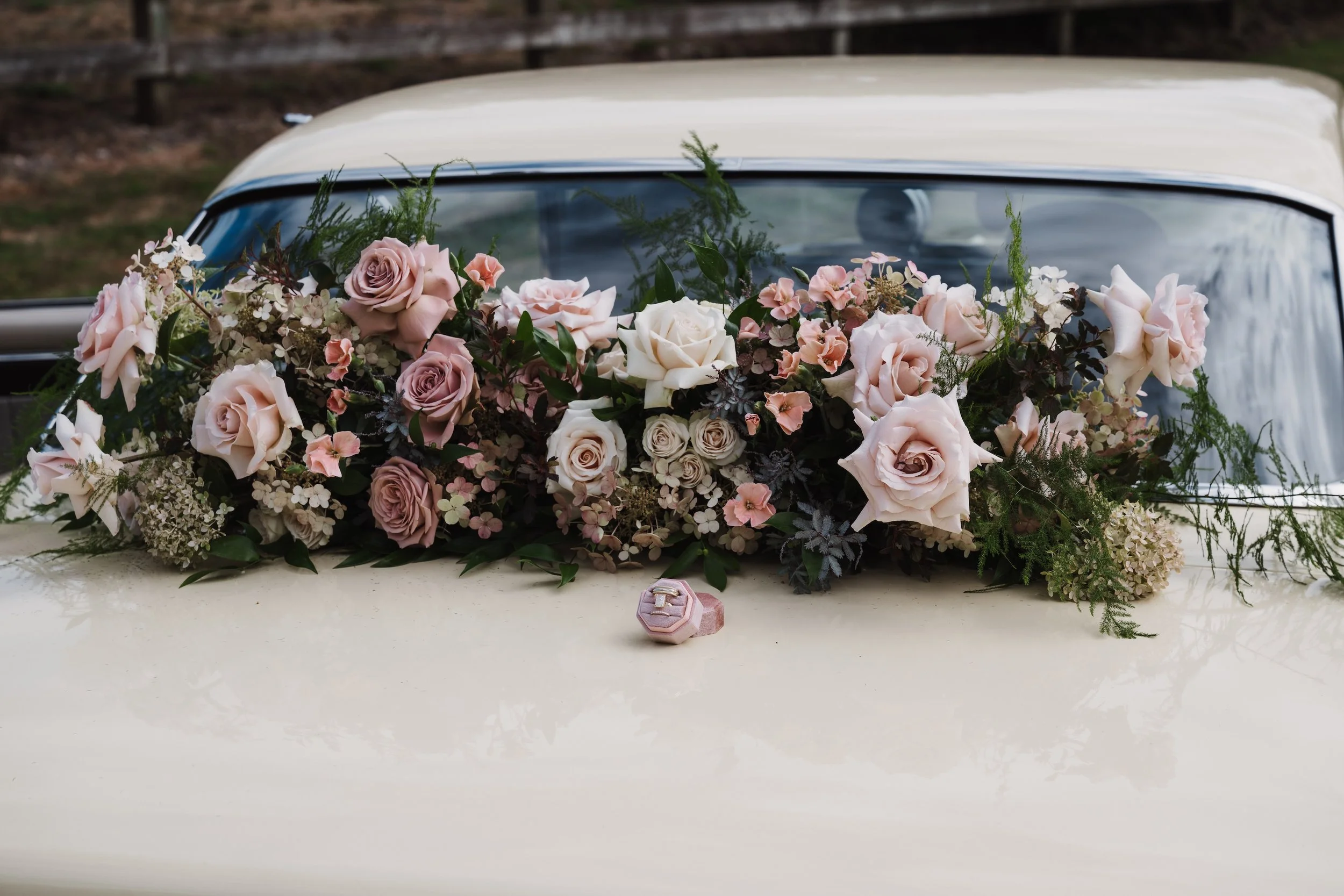 mauve and blush flowers on the back of a vintage wedding getaway car.