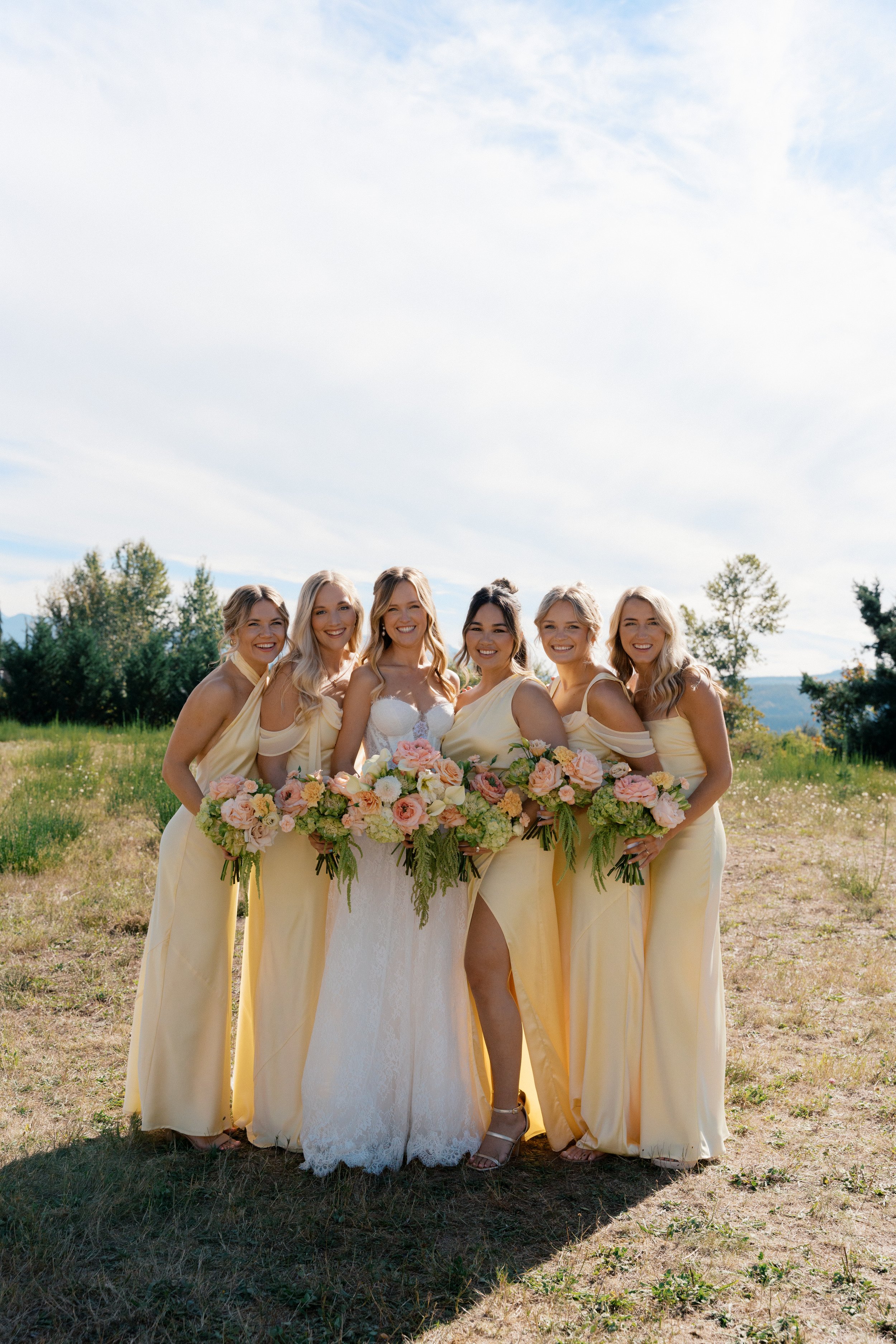 bridal party in a mountain field with romantic floral bouquets