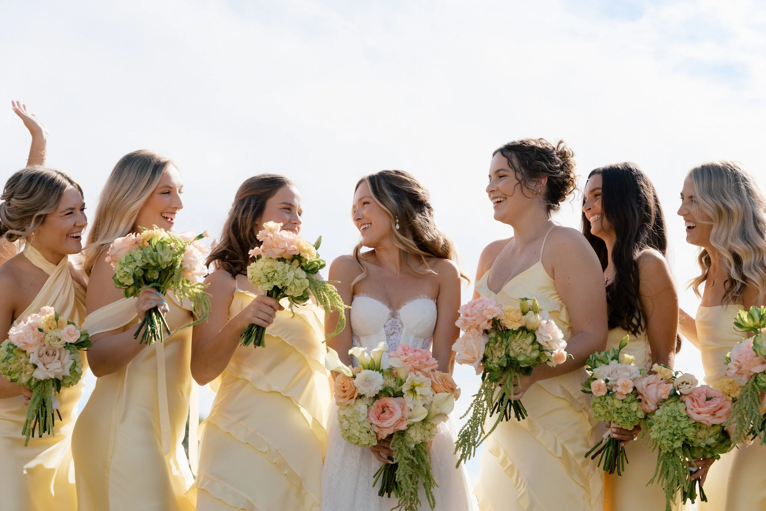 bridesmaids and bride with butter yellow dresses, peach, yellow and chartreuse bouquets.