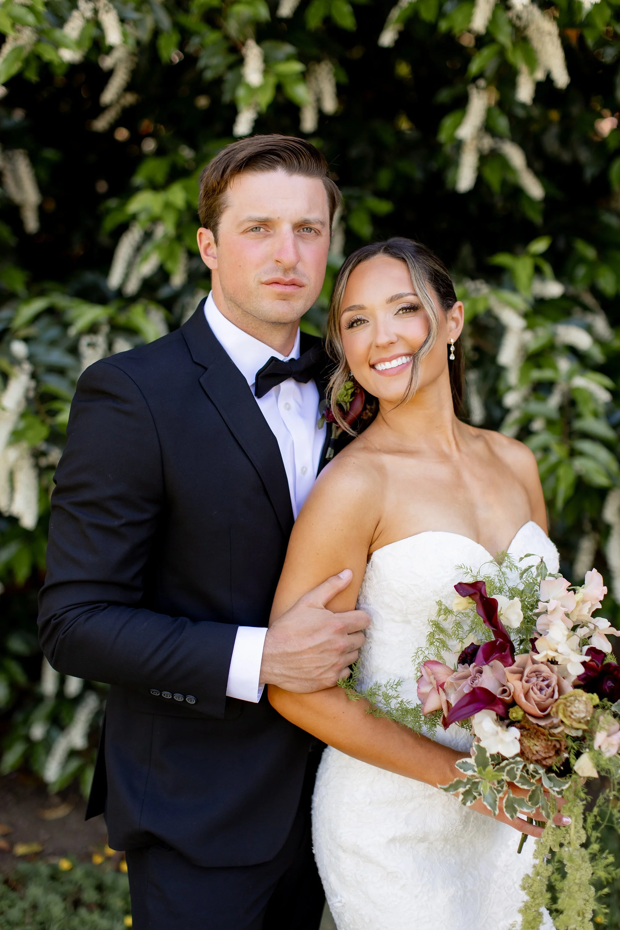 Bride and groom with a luxurious bouquet with wine colored calla lilies and mauve roses