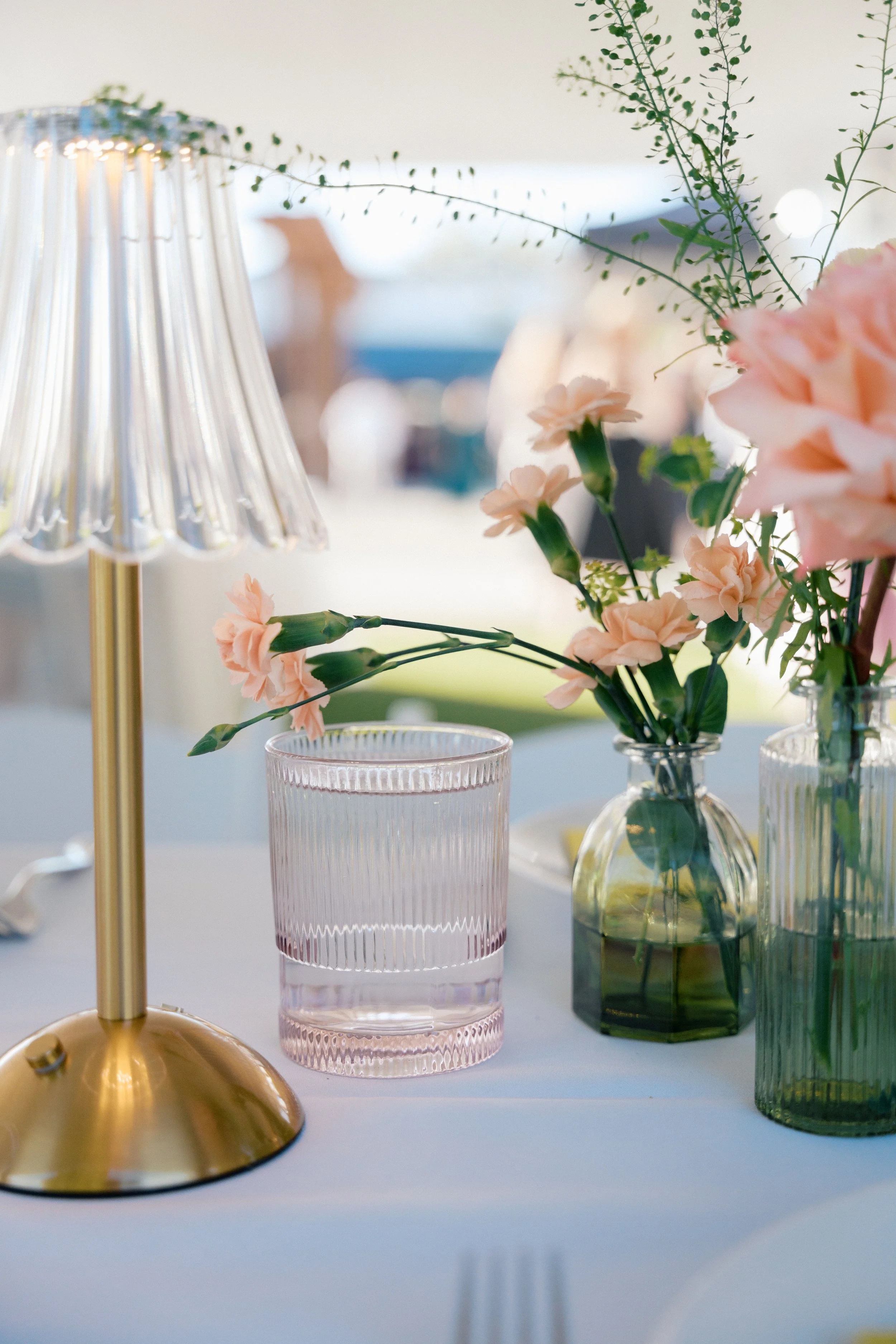 bud vases with assorted peach florals on a white tablecloth.