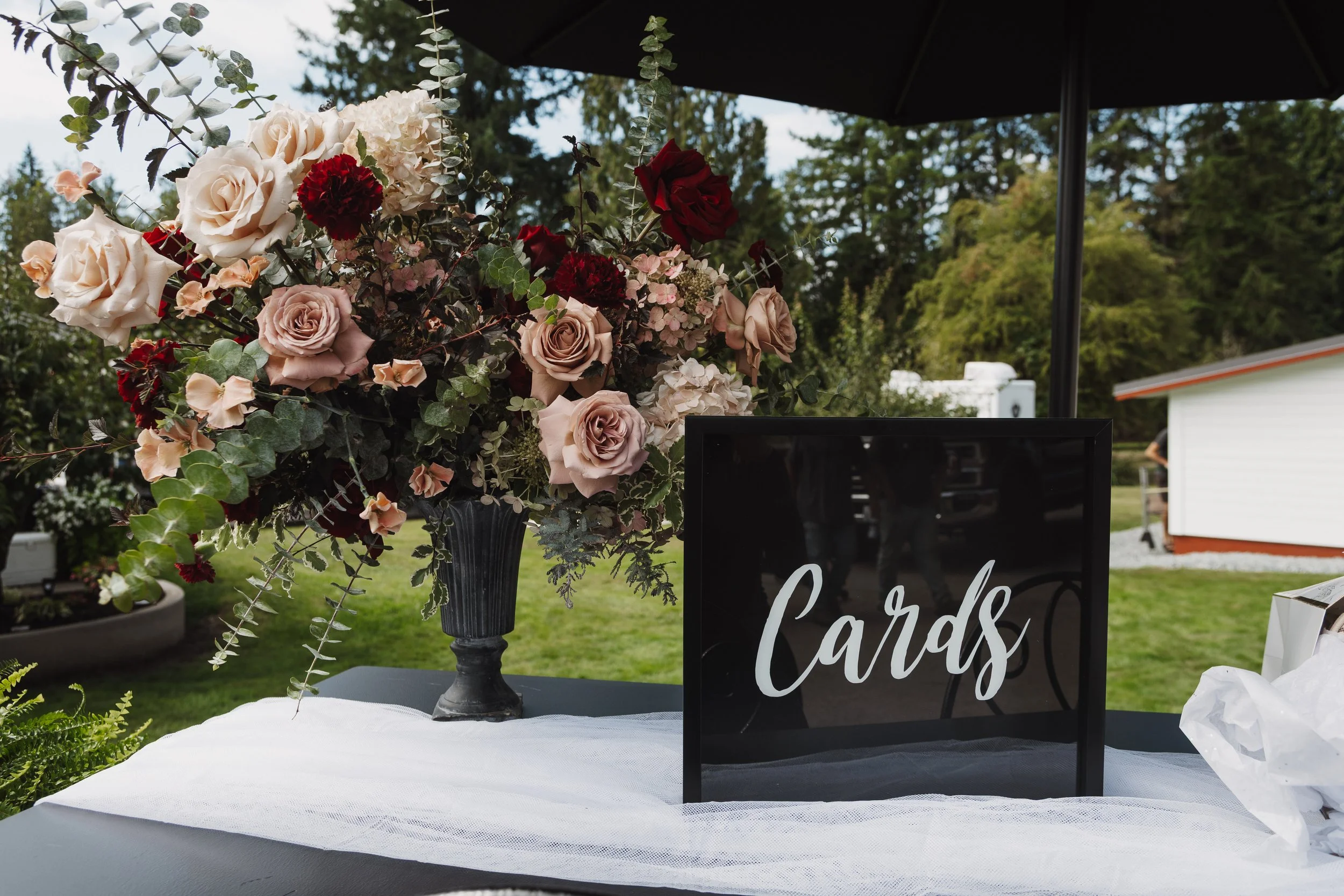 Mauve and burgundy floral arrangement at cards and gift table for wedding