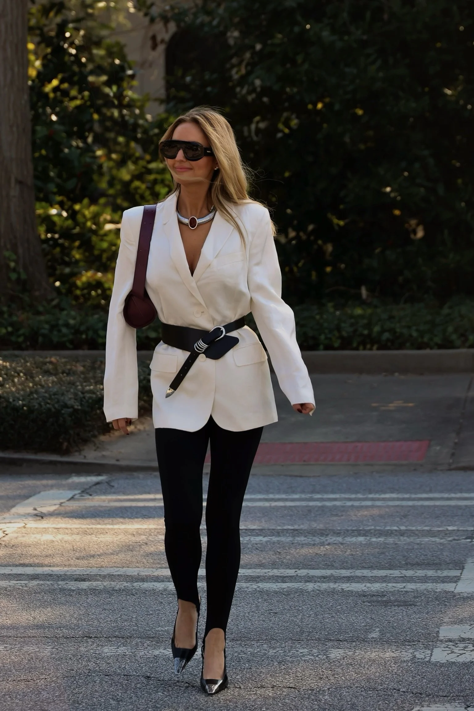 Styled by Virginia, owner Virginia Bundy, walking across street in white belted blazer with black stirrup leggings and black heels