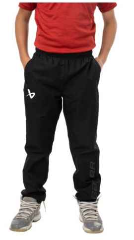 Person wearing a red shirt and black athletic pants with white text, standing with hands in pockets, wearing sneakers.