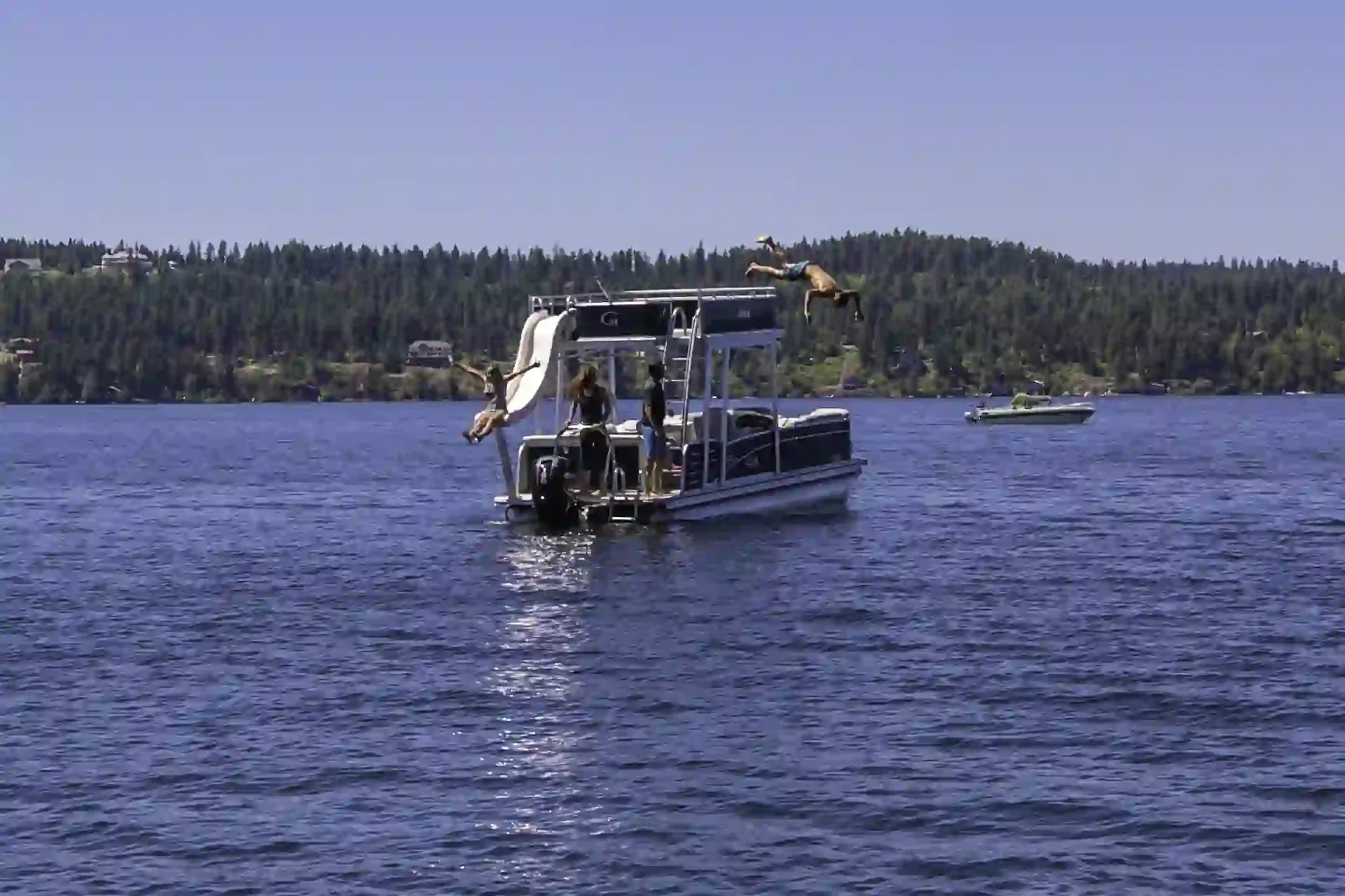 A family playing and diving off a Funship on the lake