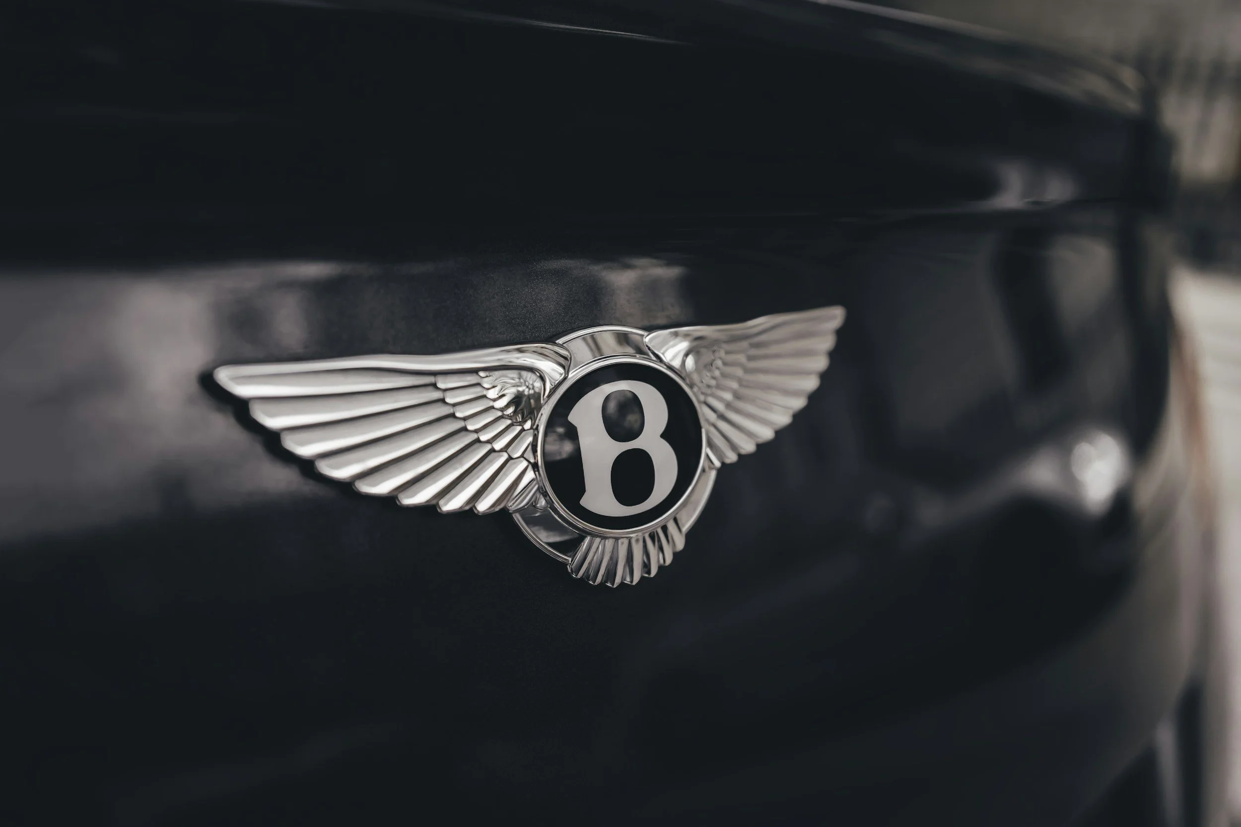 bentley logo on back of blue colored trunk of a car