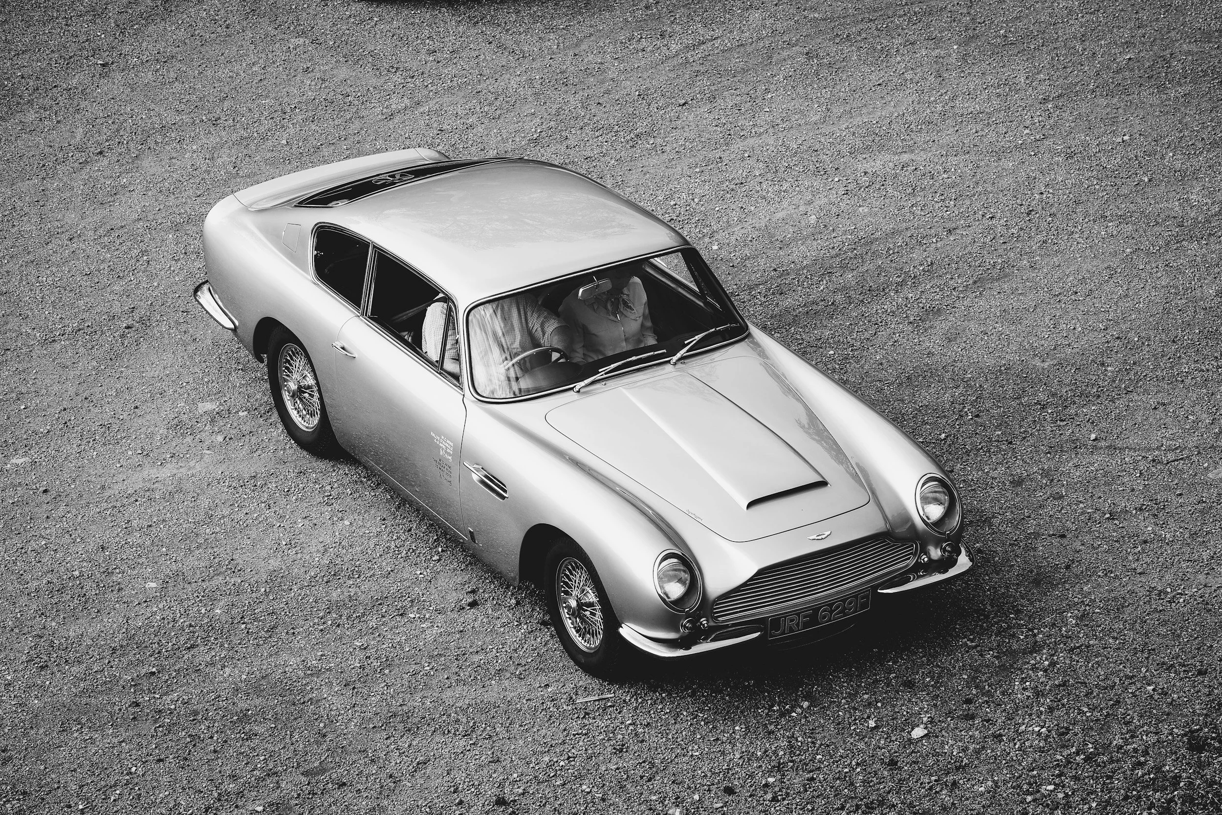 black and white picture old classic car in gravel lot parked